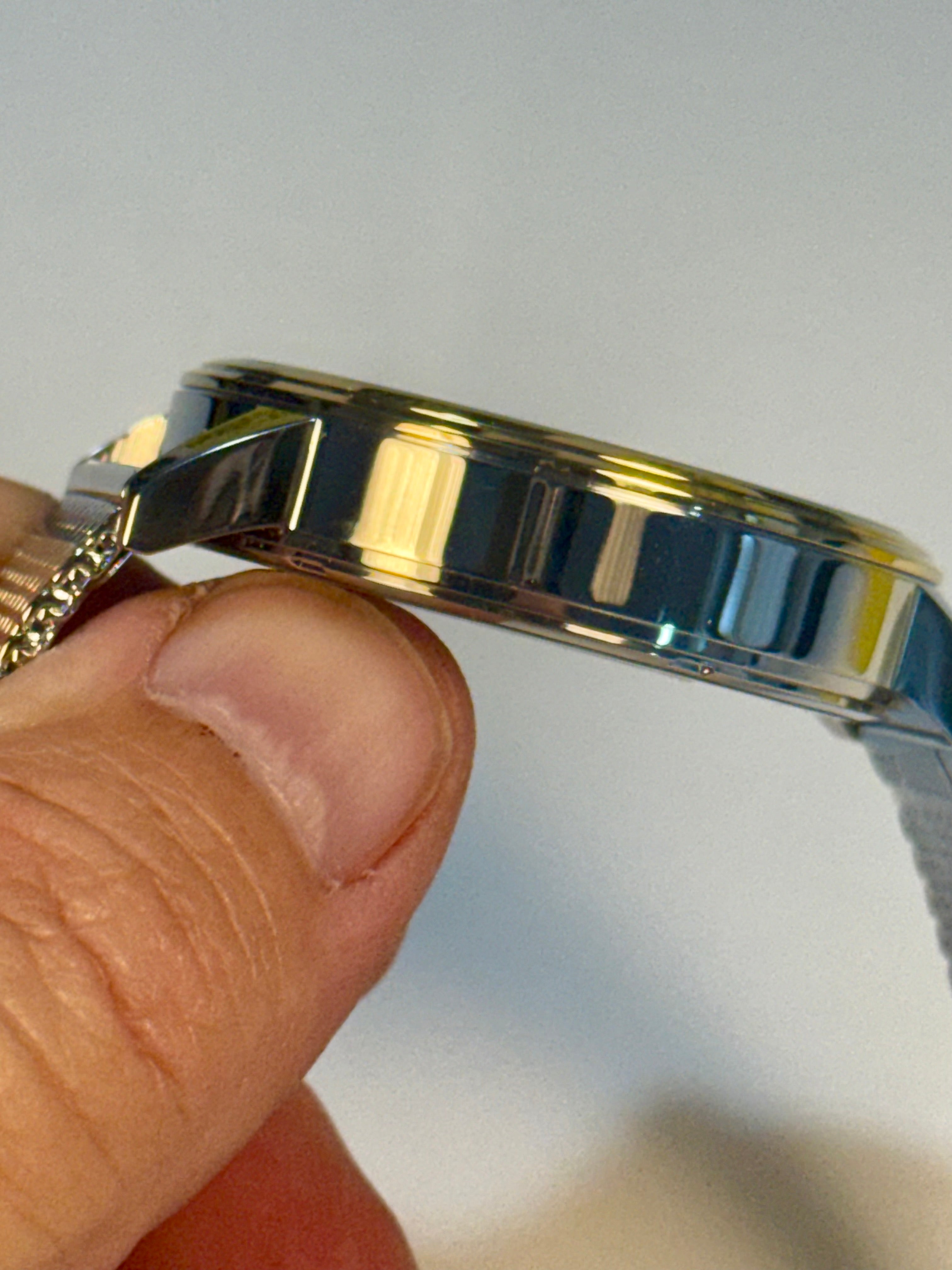 Close-up of a hand holding a Invicta Mens Specialty watch against a neutral background