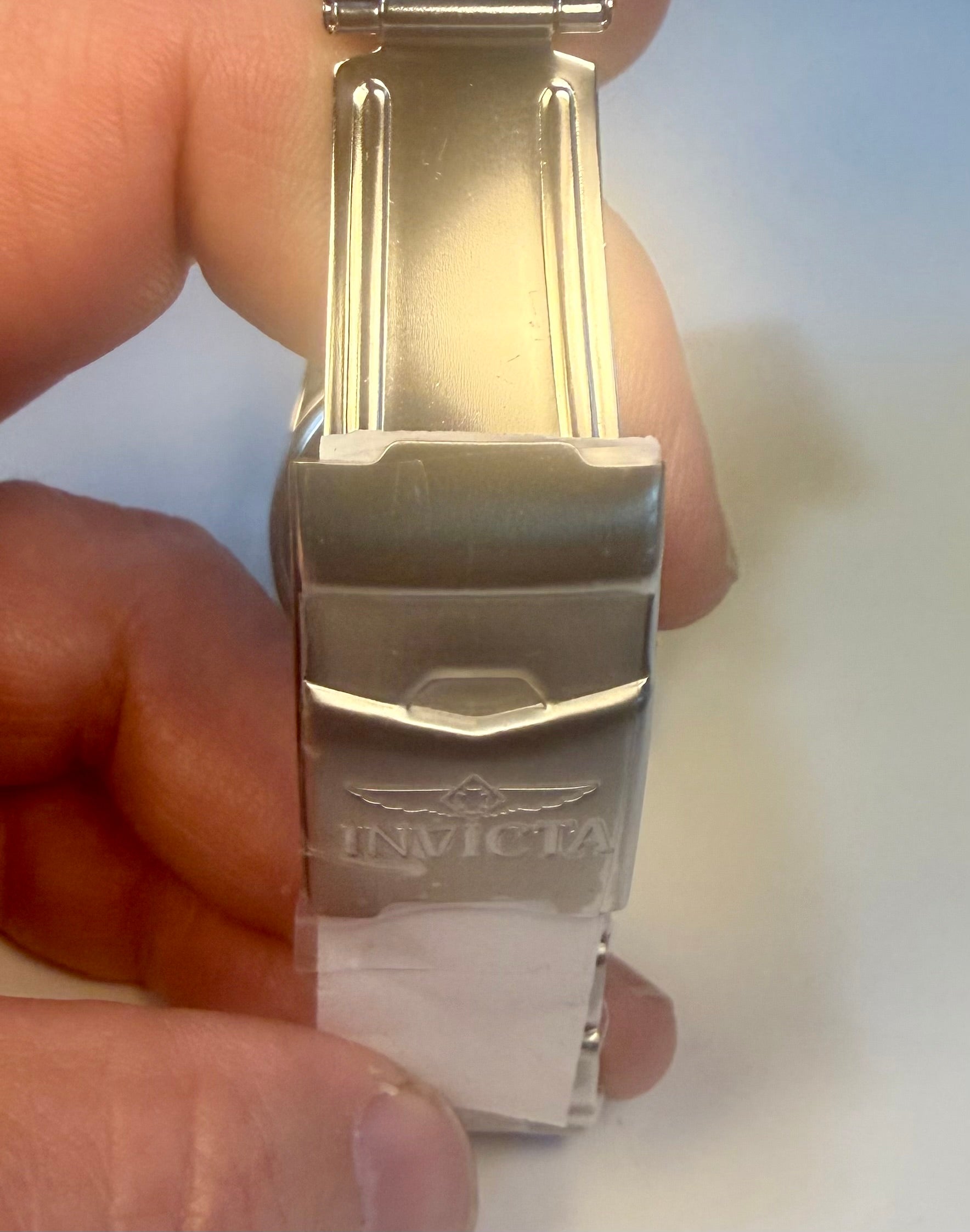 Mens 43mm Pro Diver buckle with 'Invicta' branding held by a hand against a light background