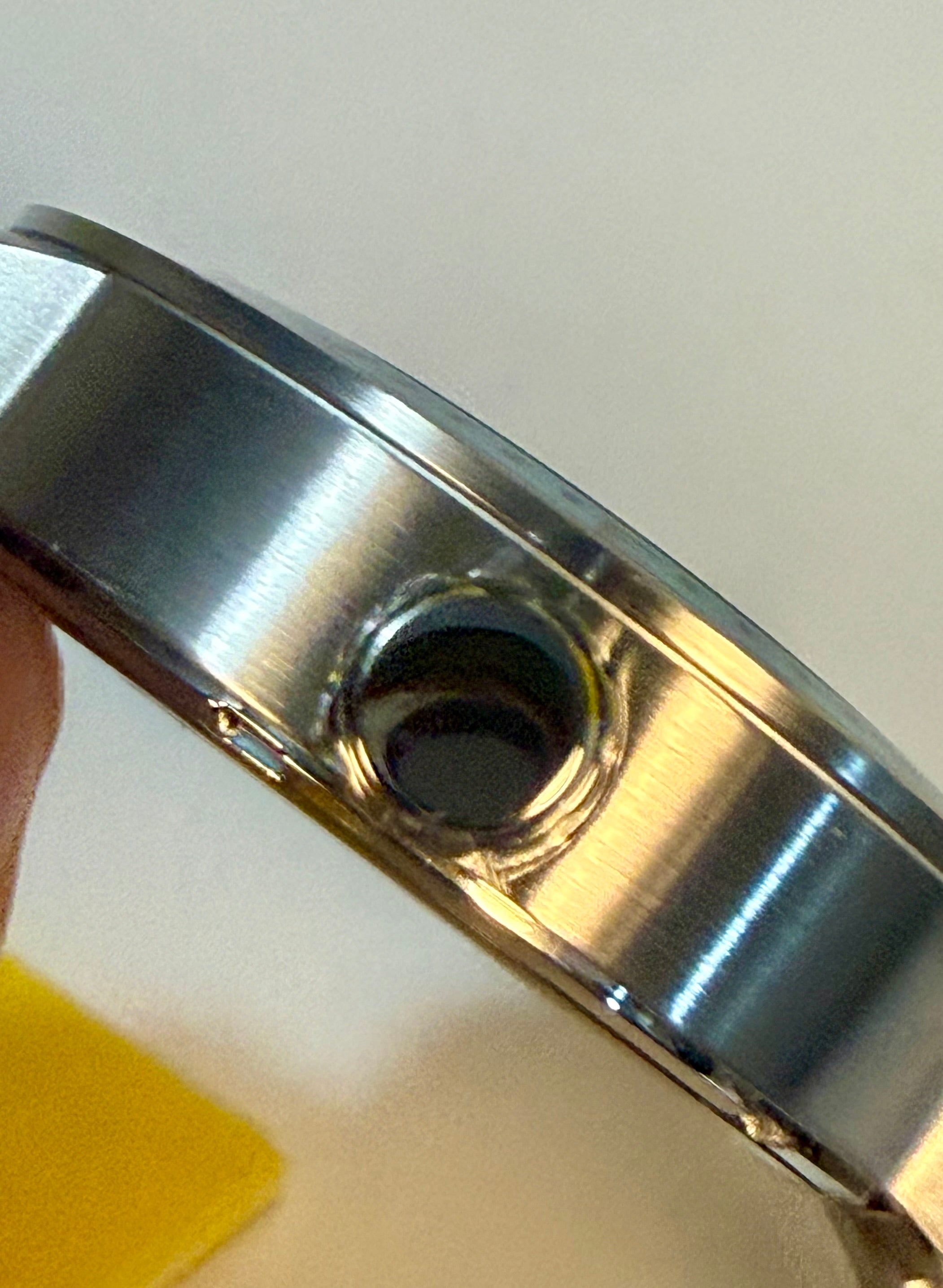 Close-up of a metallic object with a central hole on a white background