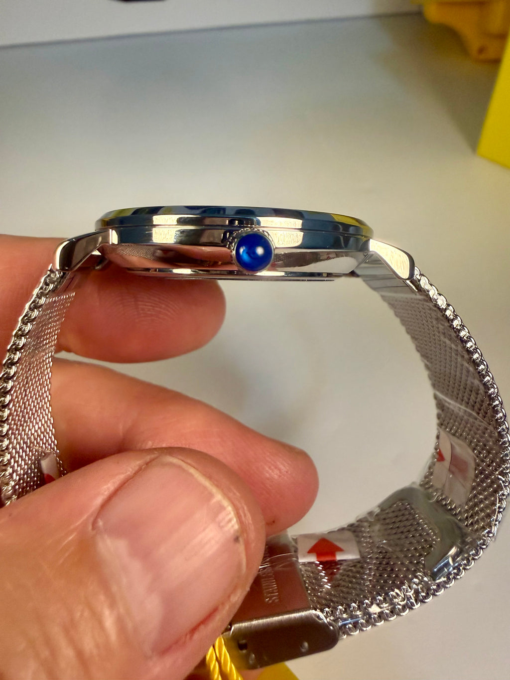Invicta Angel Starlight  with a blue gemstone held by a hand on a white background