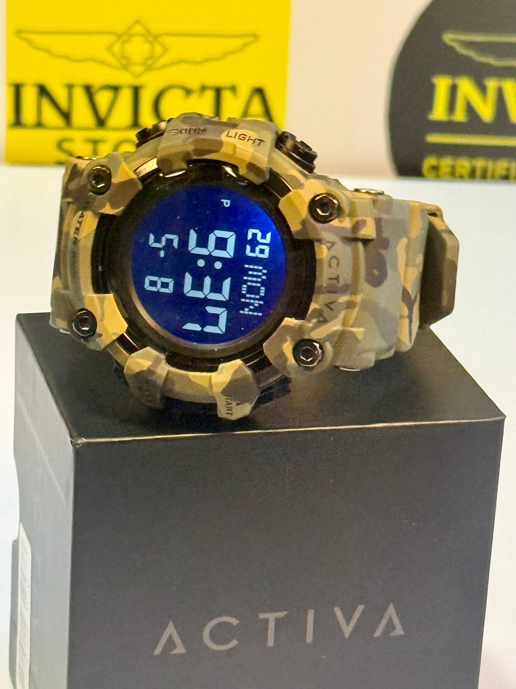 Activa X By Invicta Camouflage digital watch on a gray stand with Invicta branding in the background