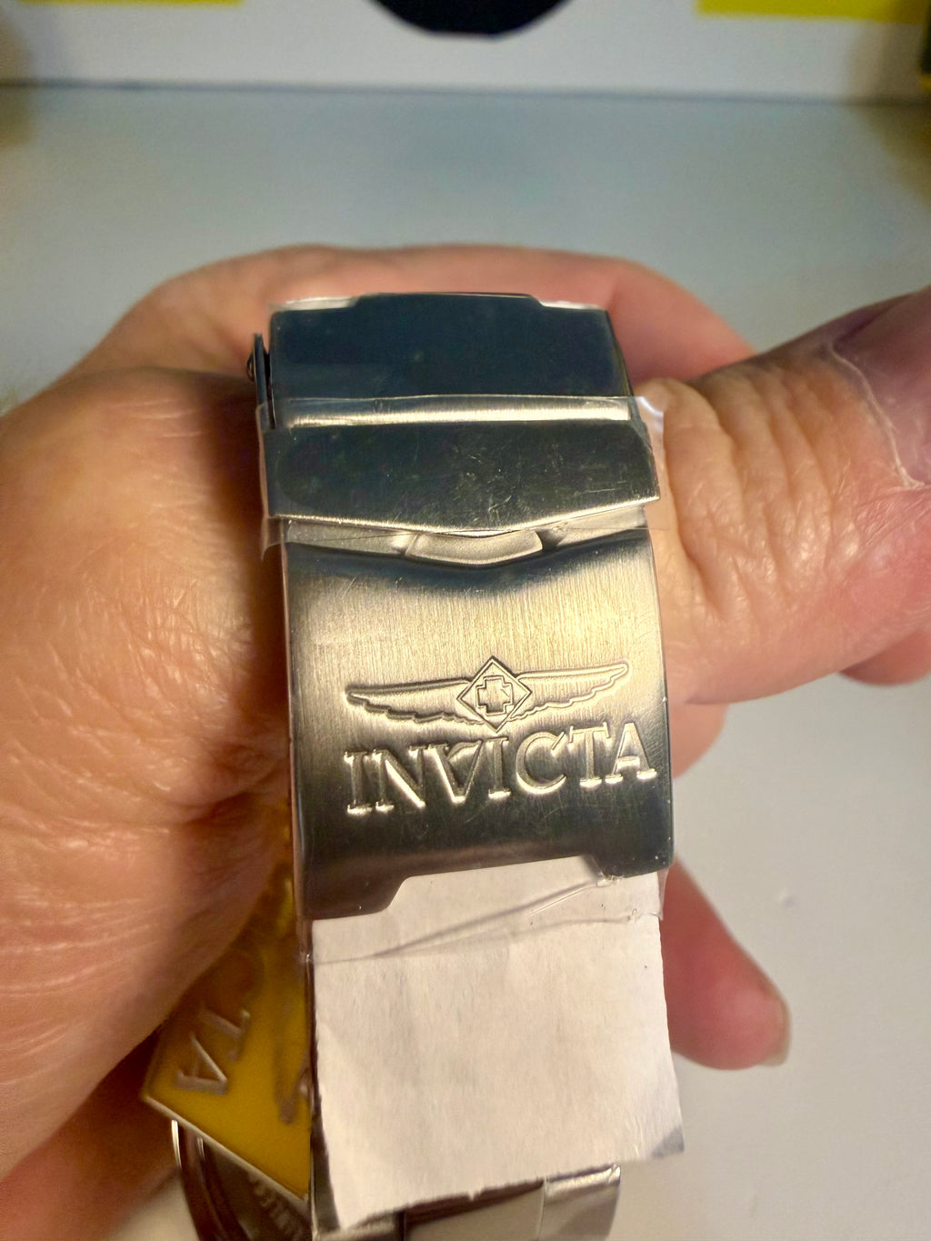 Silver Invicta watch band held in a hand with a blurred background