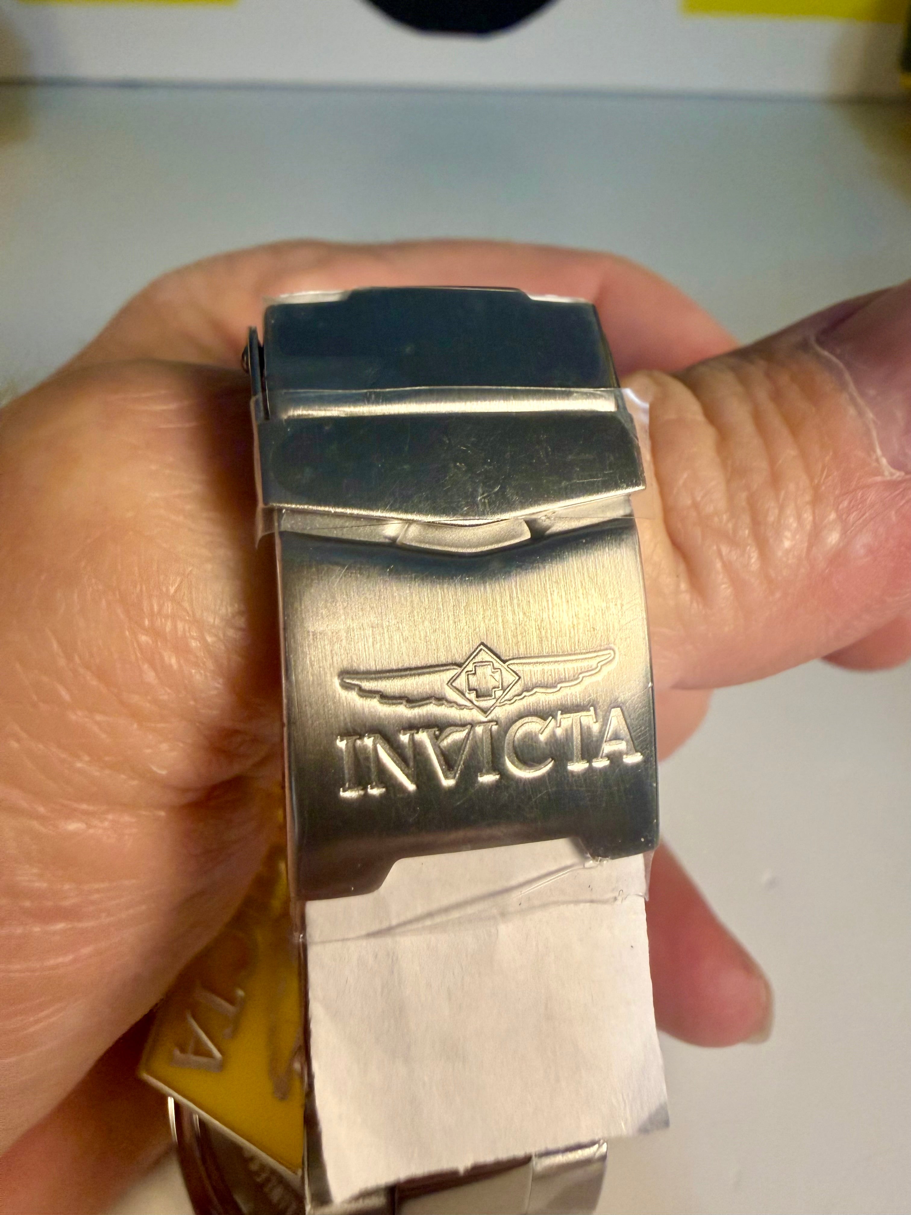 Silver Invicta watch band held in a hand with a blurred background