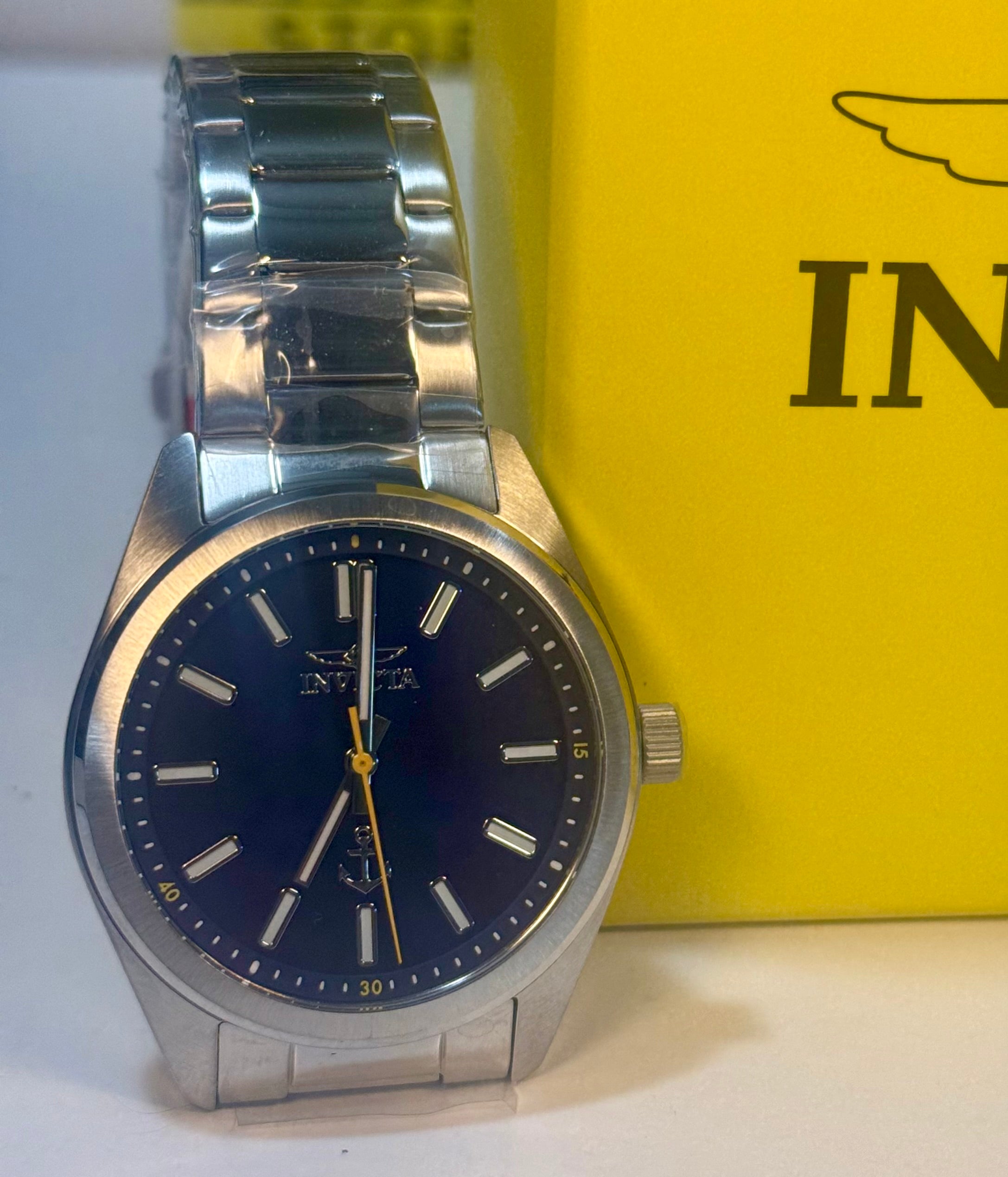 Invicta Ocean Voyage 41mm  Silver watch with a blue face on a white surface with an Innis logo in the background.