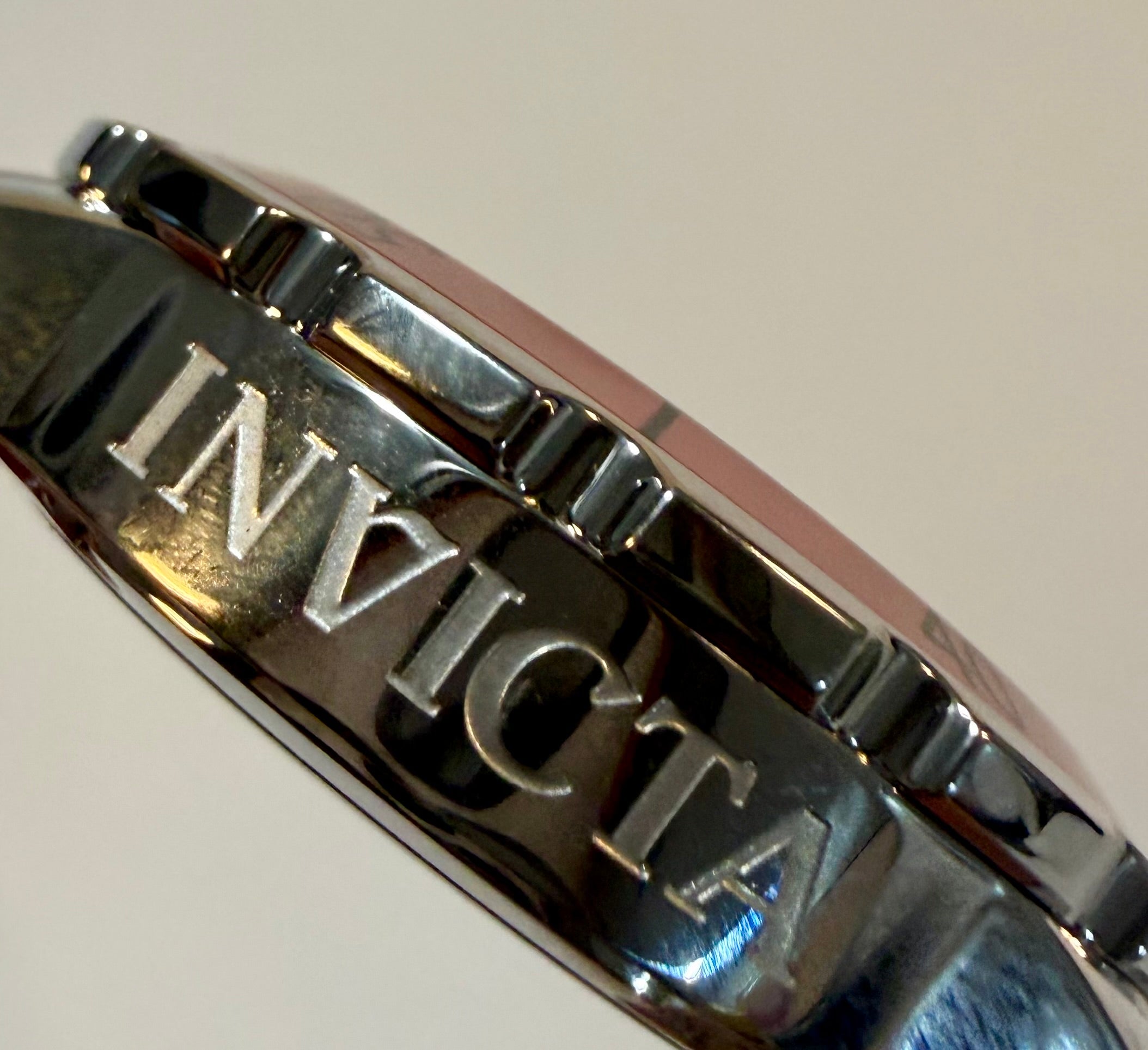 Close-up of a silver Invicta watch band on a light background