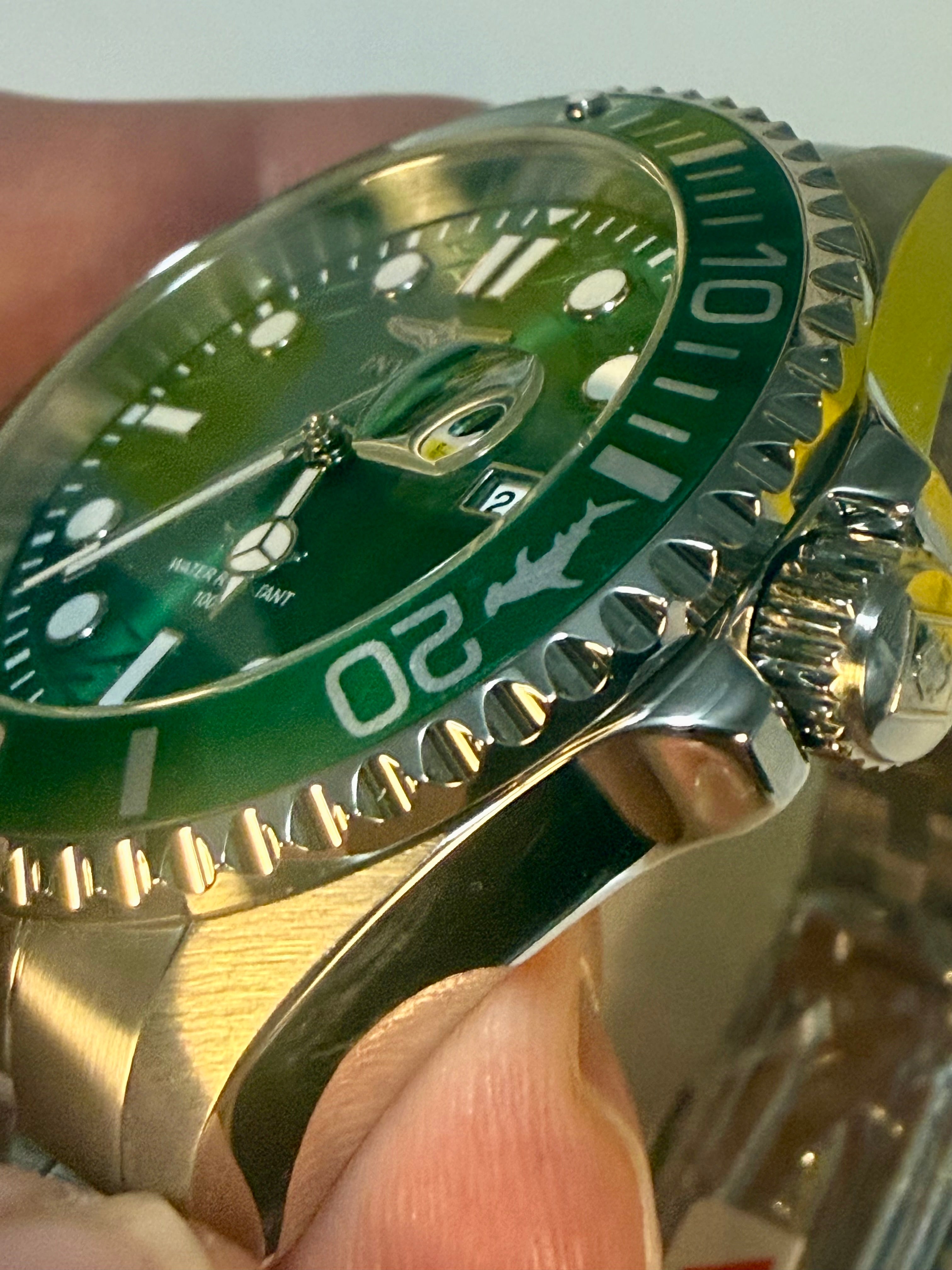 Invicta Mens Pro Diver 43mm Close-up of a green and gold watch with a visible brand logo.