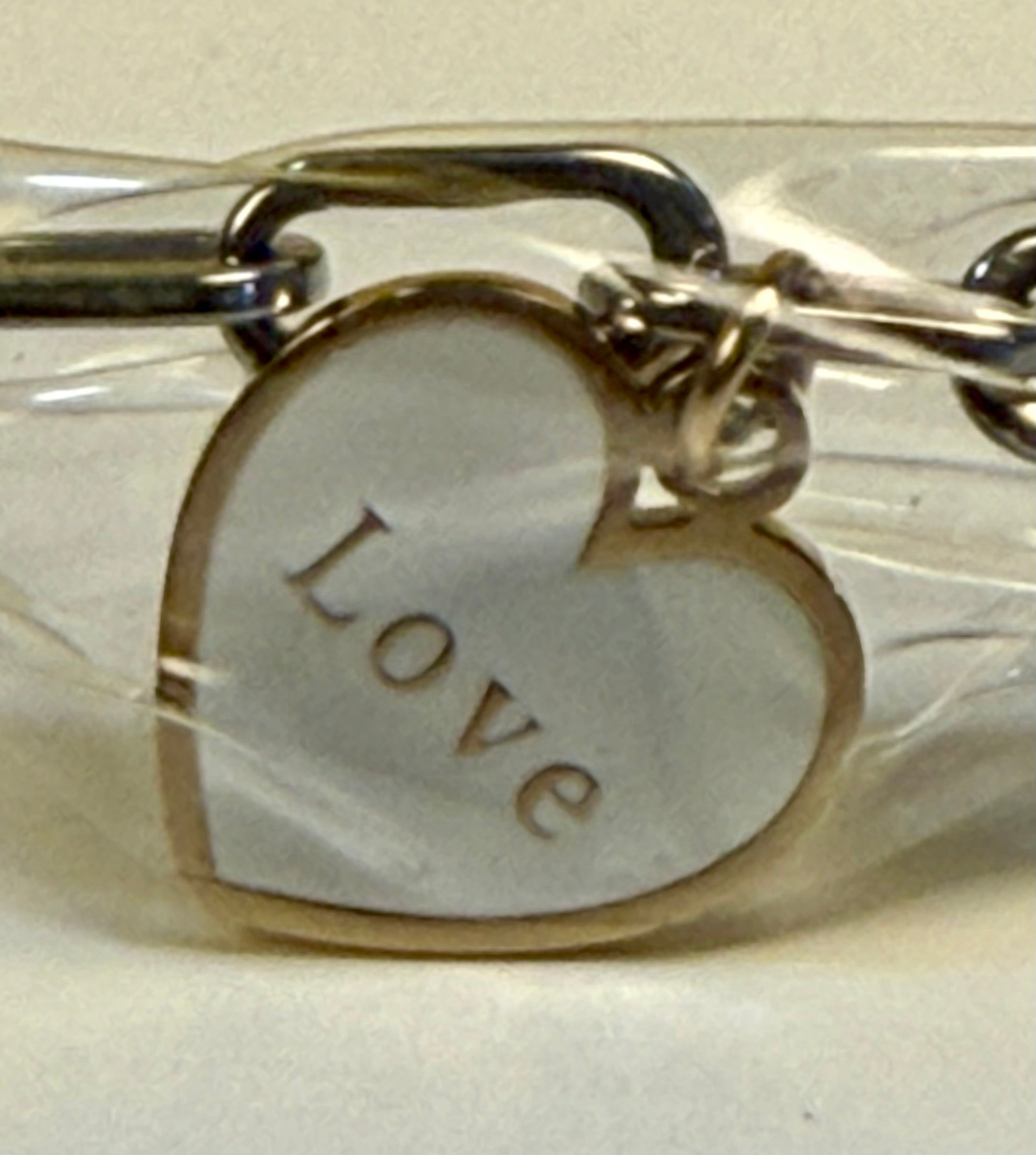 Heart-shaped charm with 'LOVE' engraving on a chain.