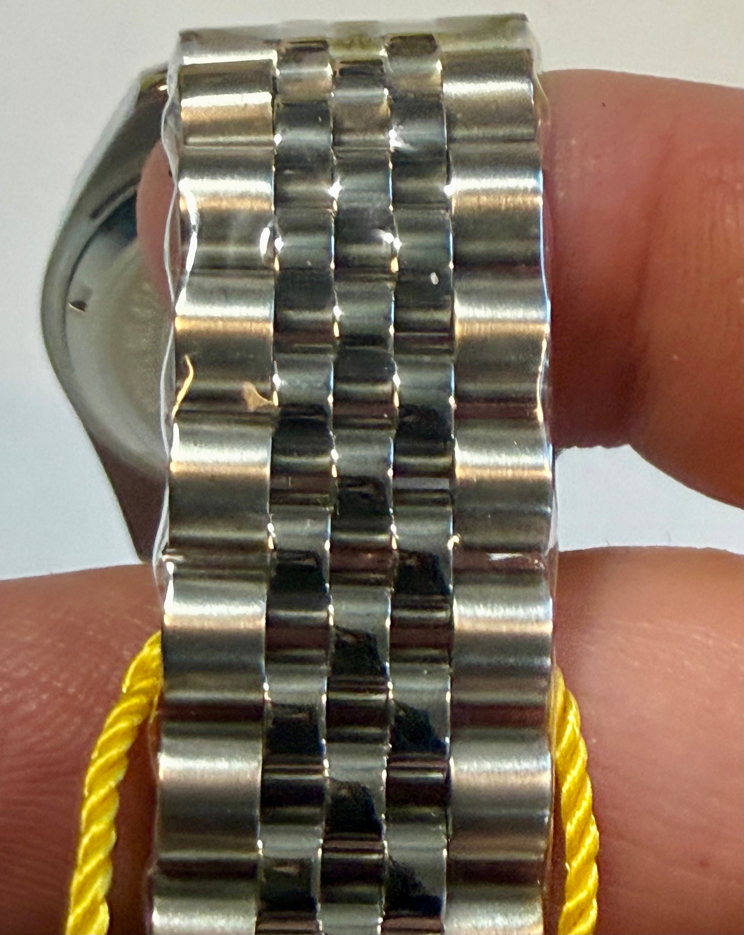 Close-up of a silver watch bracelet on a wrist with a white background