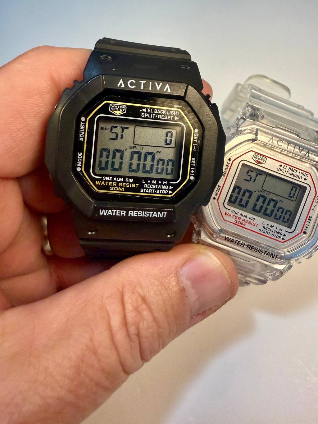 Activa ebony and Ivory Bundle Hand holding a black digital watch with 'Activa' branding, next to its packaging.
