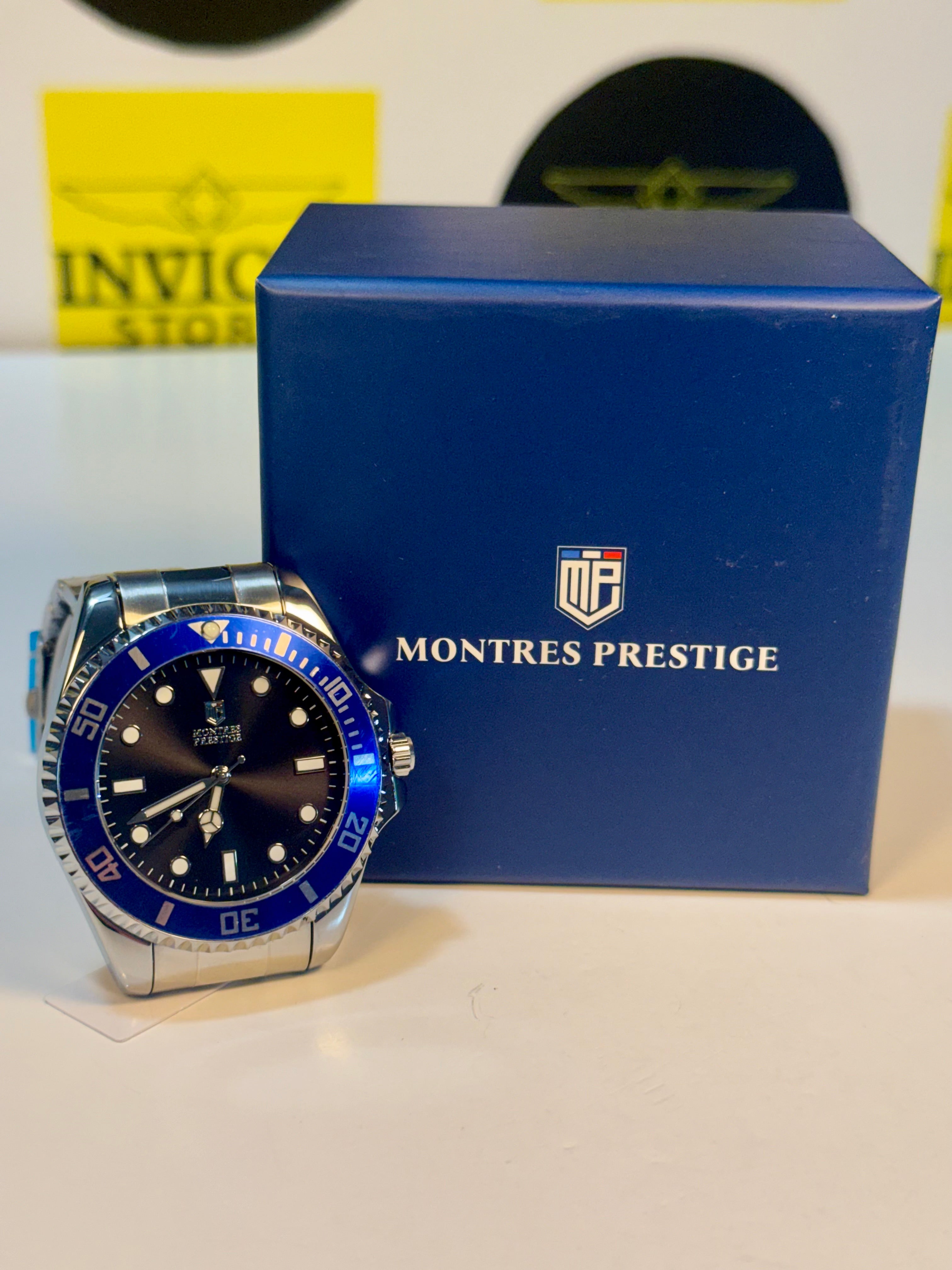 Montres Prestige 42mm Mens Pro Diver  watch with blue bezel and face on a white surface with a blue box in the background.