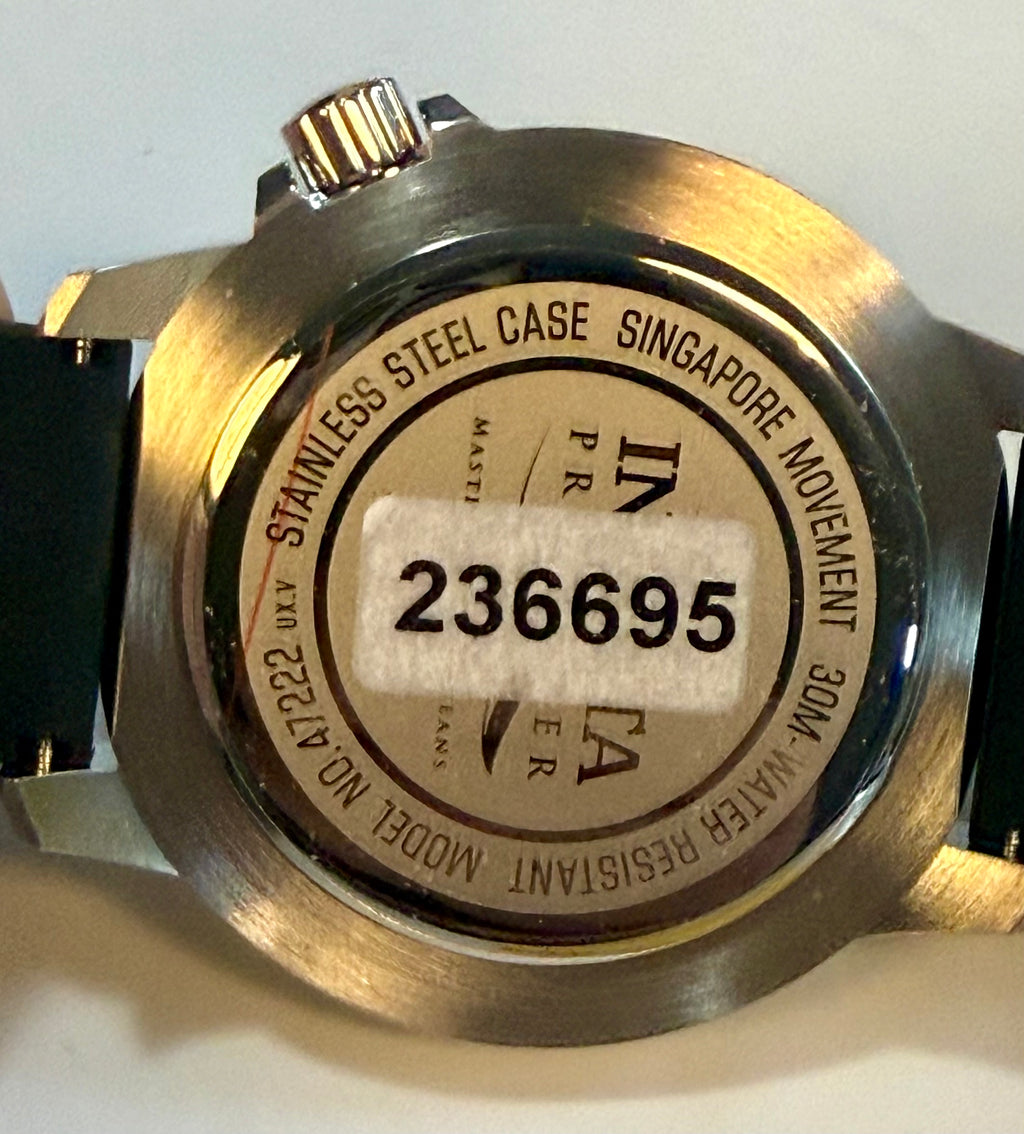 Close-up of a watch case with branding and model number on a light gray background