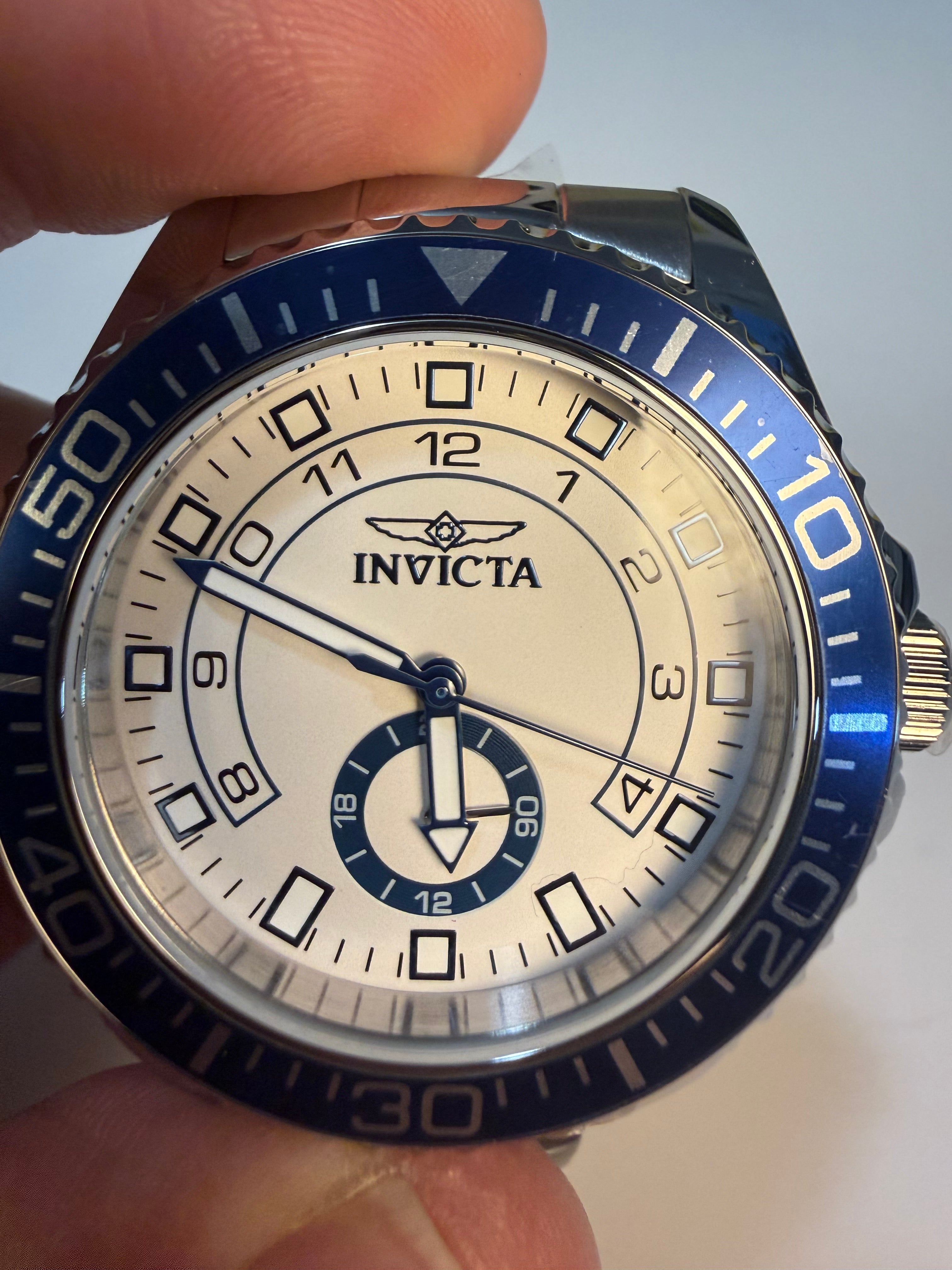 Invicta Mens Pro Diver watch with blue and silver accents held in a hand against a neutral background