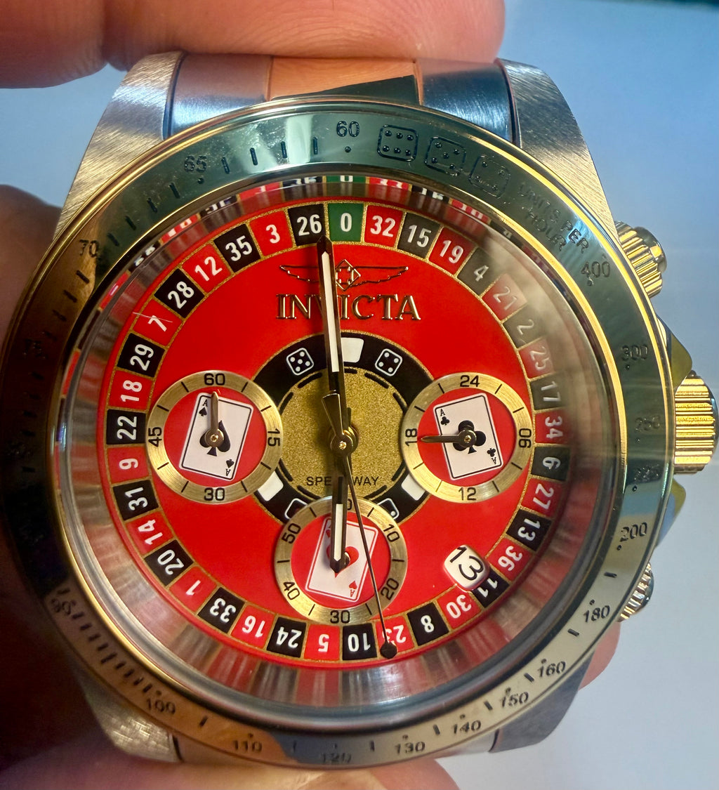 Invicta Speedway Monte Carlo Gold and red Invicta watch held in a hand with a white background