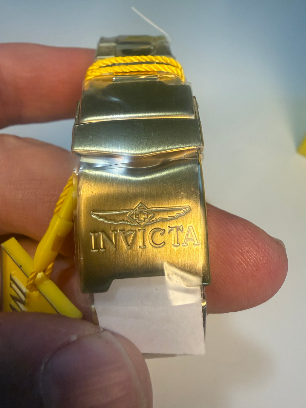 Invicta Speedway Monte Carlo Gold Invicta watch band held by a hand with a white background