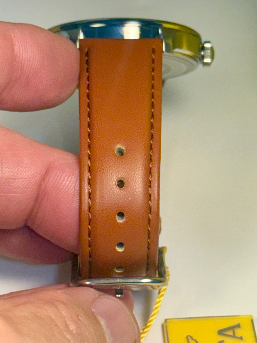 Mens Celestial Blue Sunray Dial Brown leather watch strap held by a hand with a blurred background