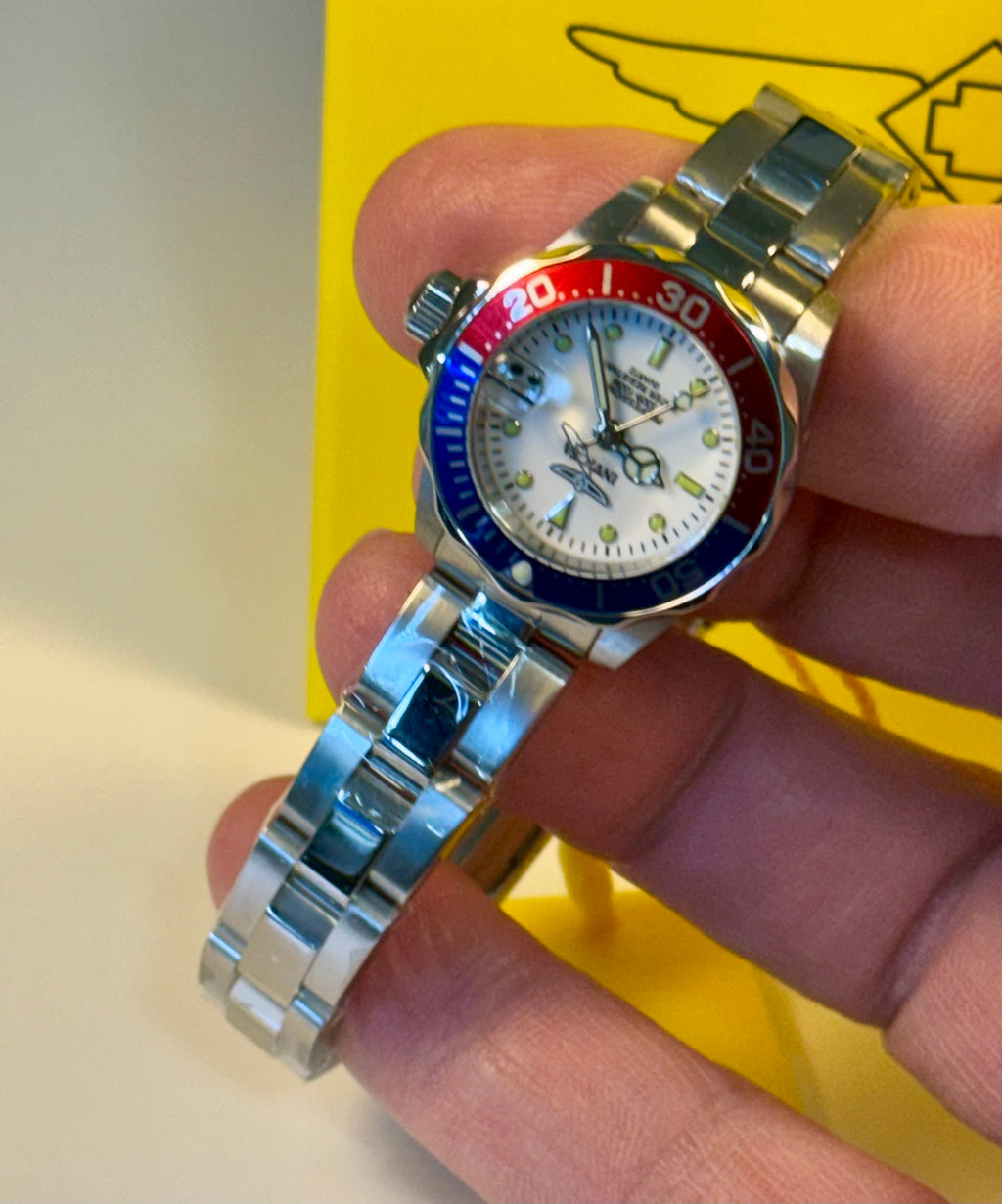 Ladies Pro Diver  watch with a colorful bezel held in a hand against a yellow background