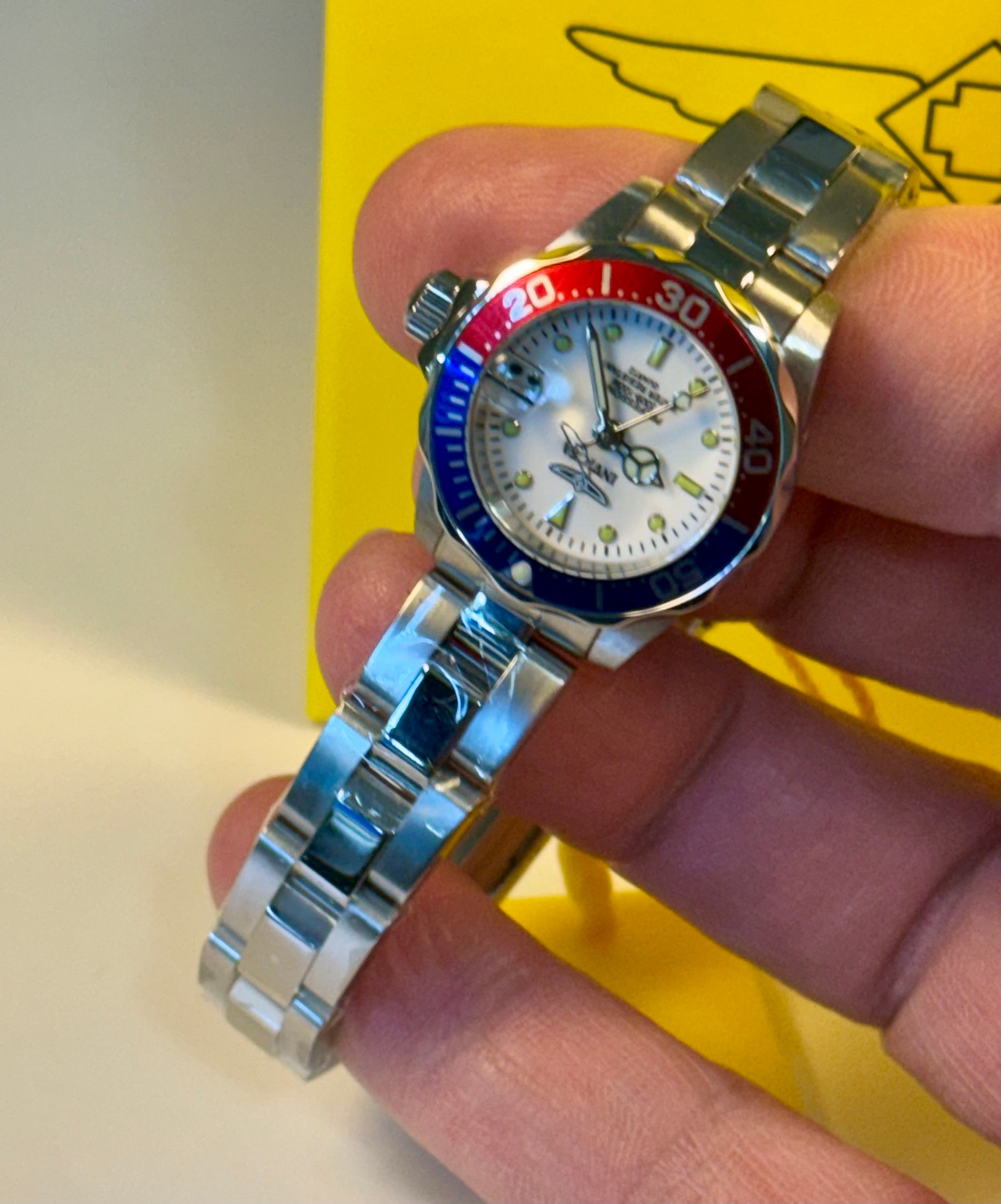 Ladies Pro Diver  watch with a colorful bezel held in a hand against a yellow background