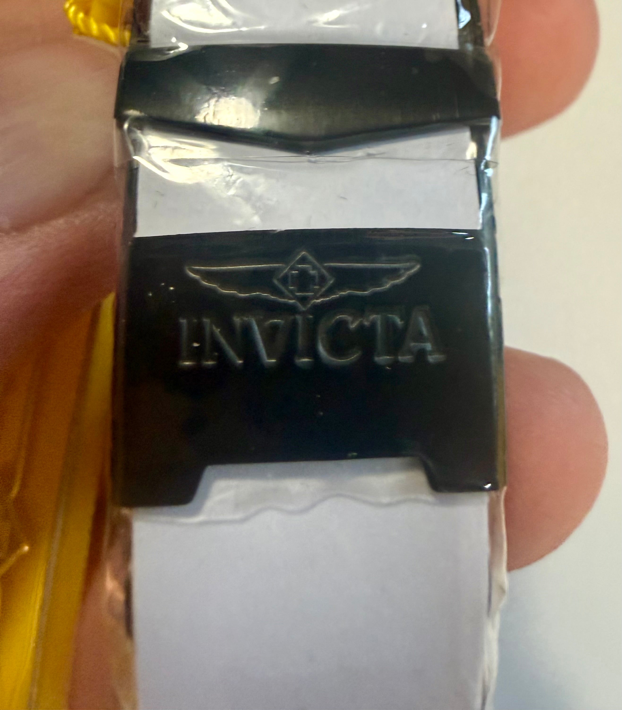 Close-up of a Invicta Mens Pro Diver Black and blue  buckle with 'Invicta' branding held between fingers.
