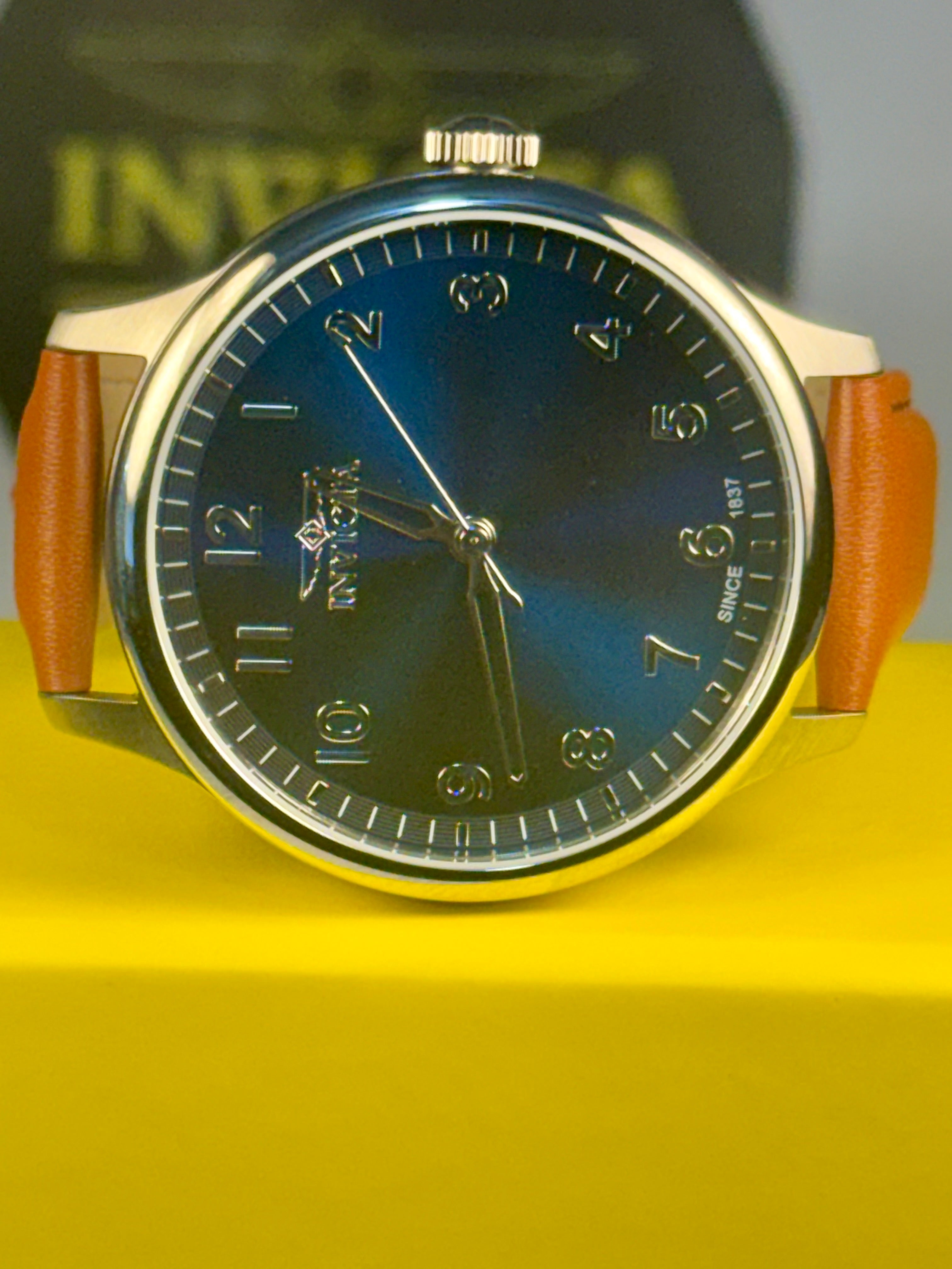 Mens Celestial Blue Sunray Dial Watch with a blue face and brown strap on a yellow surface, with 'Inval' branding in the background.