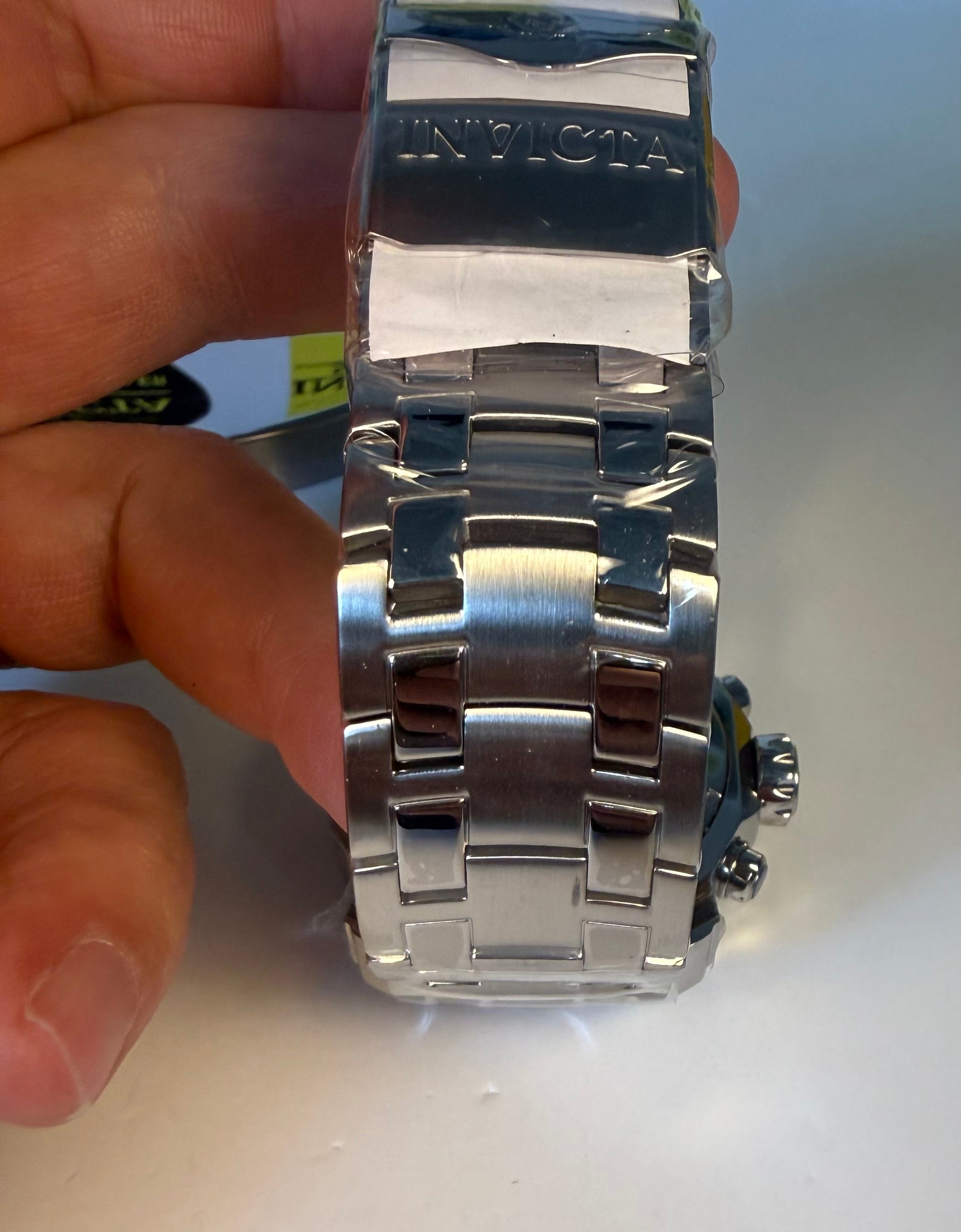 Close-up of a silver Invicta Pro Diver Scuba 48mm watch band held by a hand on a light background
