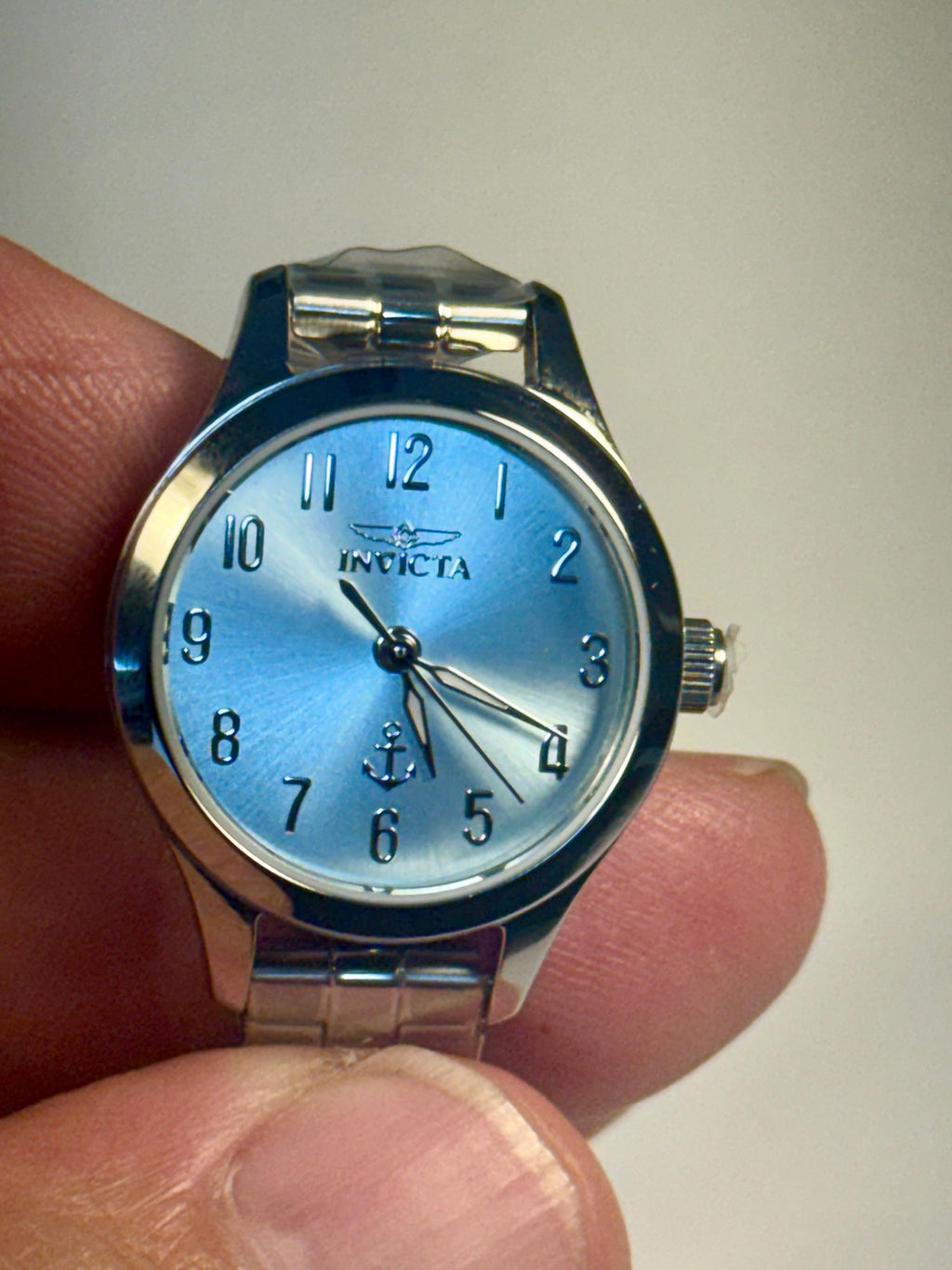 Invicta Ladies Ocean Voyage Silver watch with blue face held in hand against a plain background