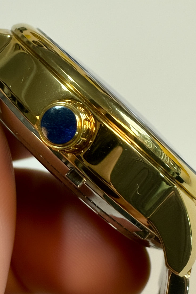 Close-up of a Invicta Mens Automatic Objet' De Art  gold watch case held between fingers