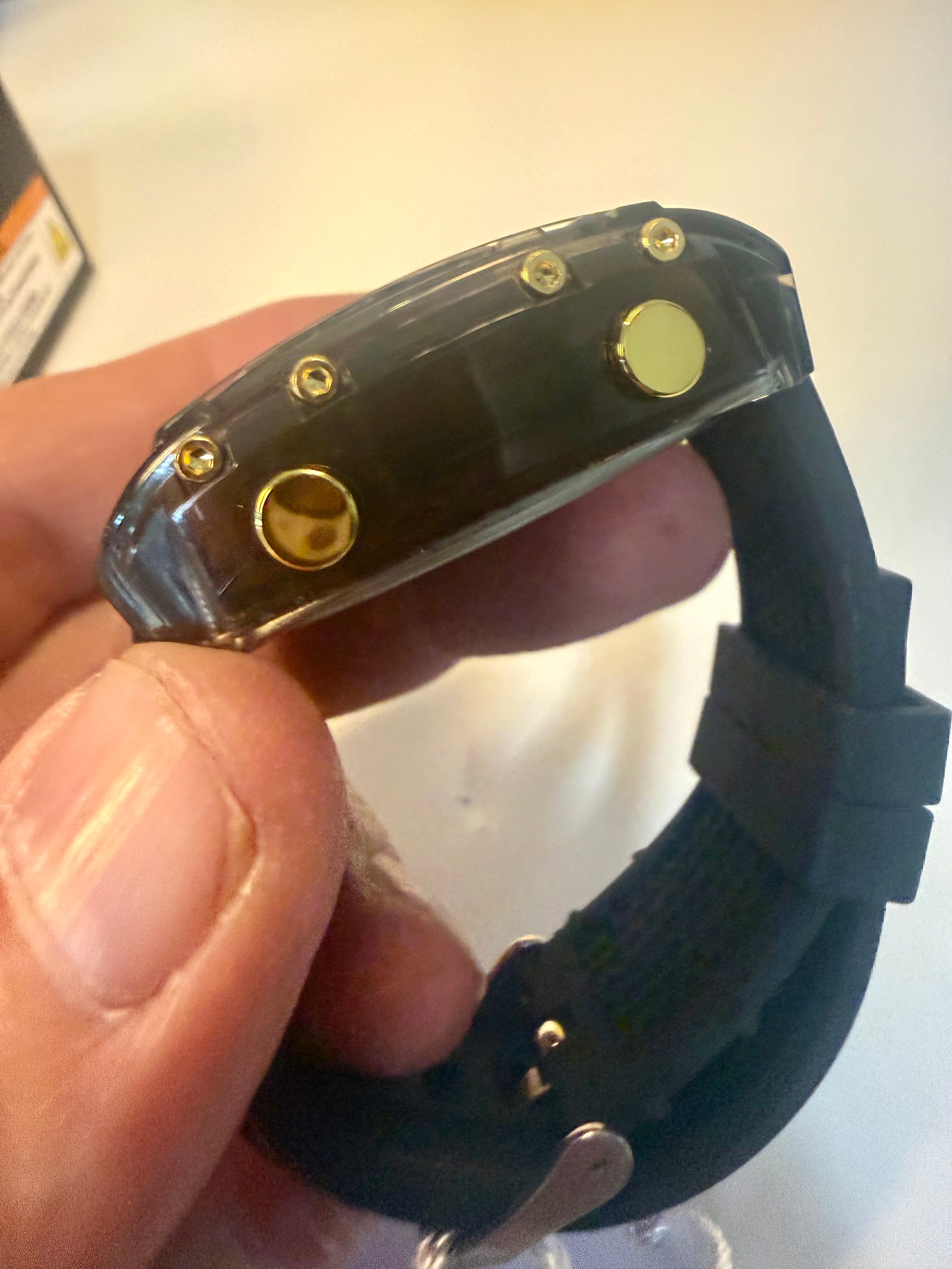 Activa X Ranger Bundlewristband with gold screws held by a hand on a white background