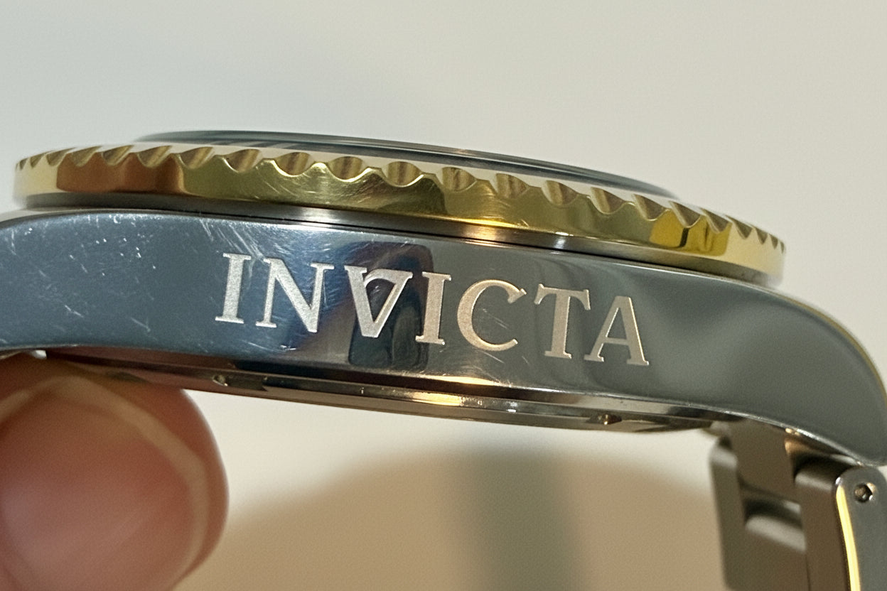 Close-up of a silver Invicta watch case with a blurred background