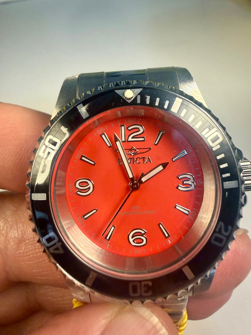 Invicta Specialty Rowan Watch with a red face held by a hand on a light background