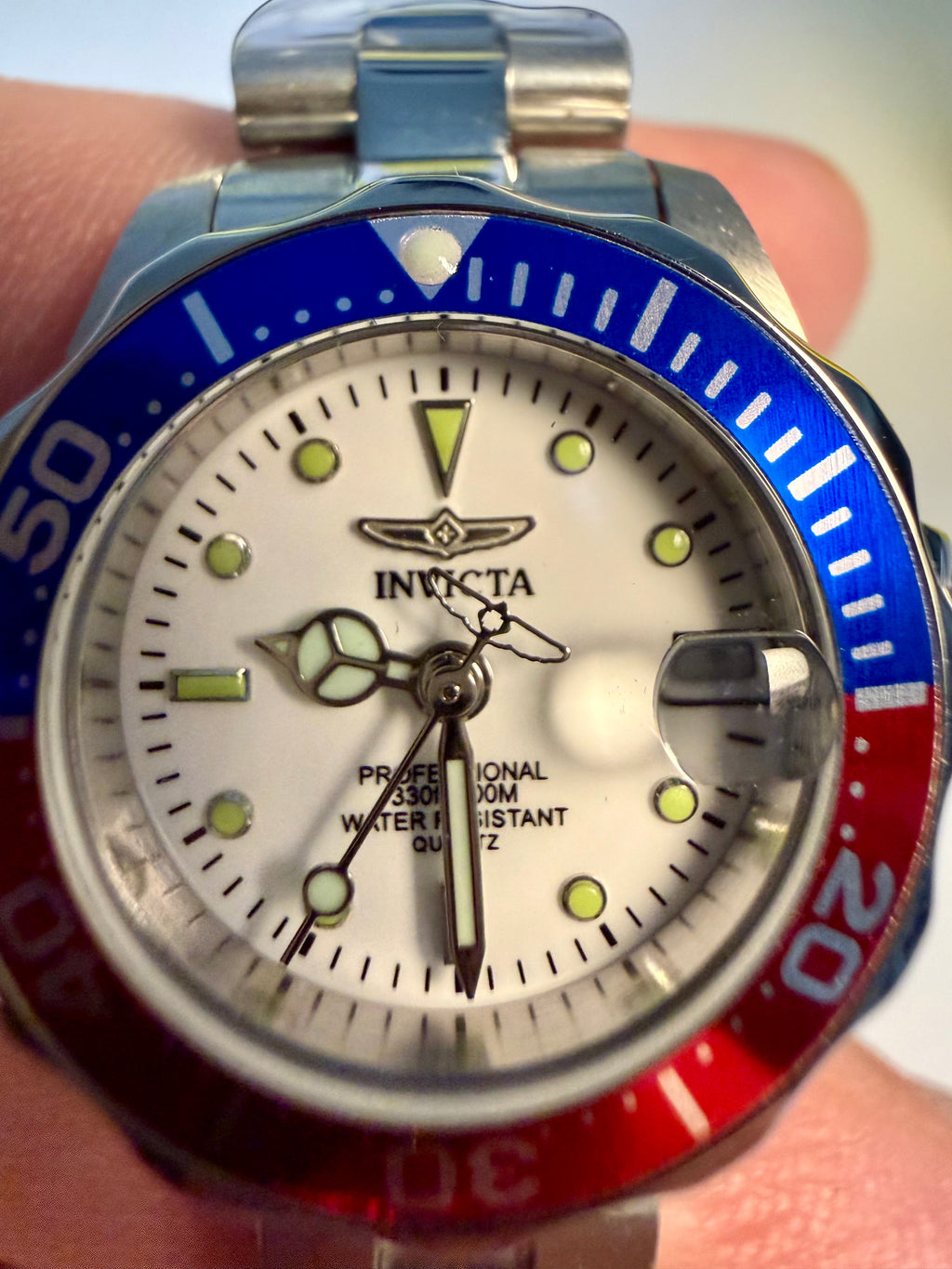 Ladies Pro Diver Invicta watch with a red and blue bezel held in hand