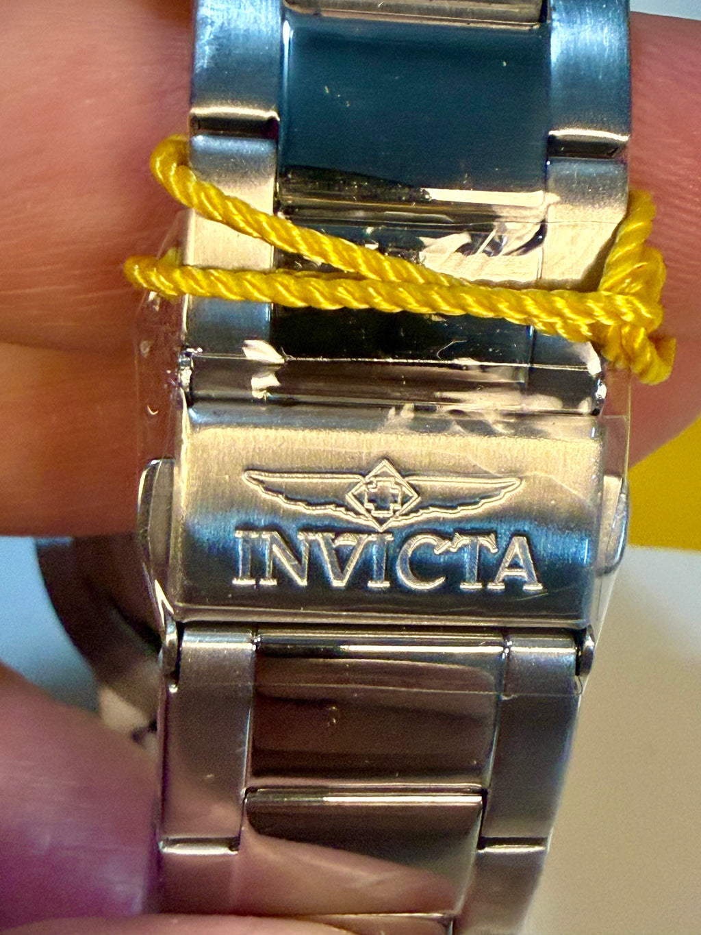 Close-up of a Invicta Specialty Gramercy 45mm Mens watch band on a wrist with a yellow cord.