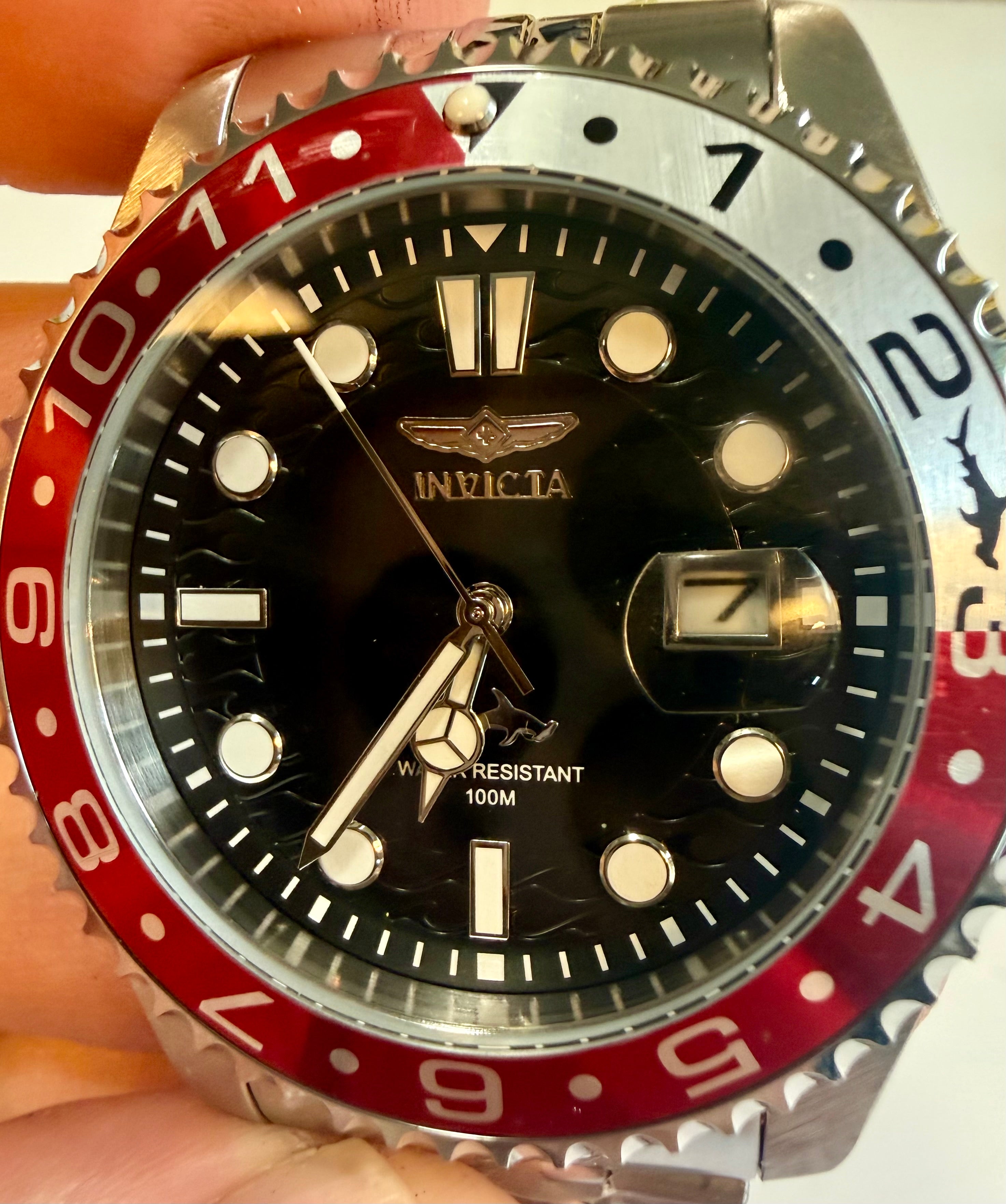 Invicta Mens Pro Diver 43mm Heritage  watch with red and silver bezel held by a hand on a white background