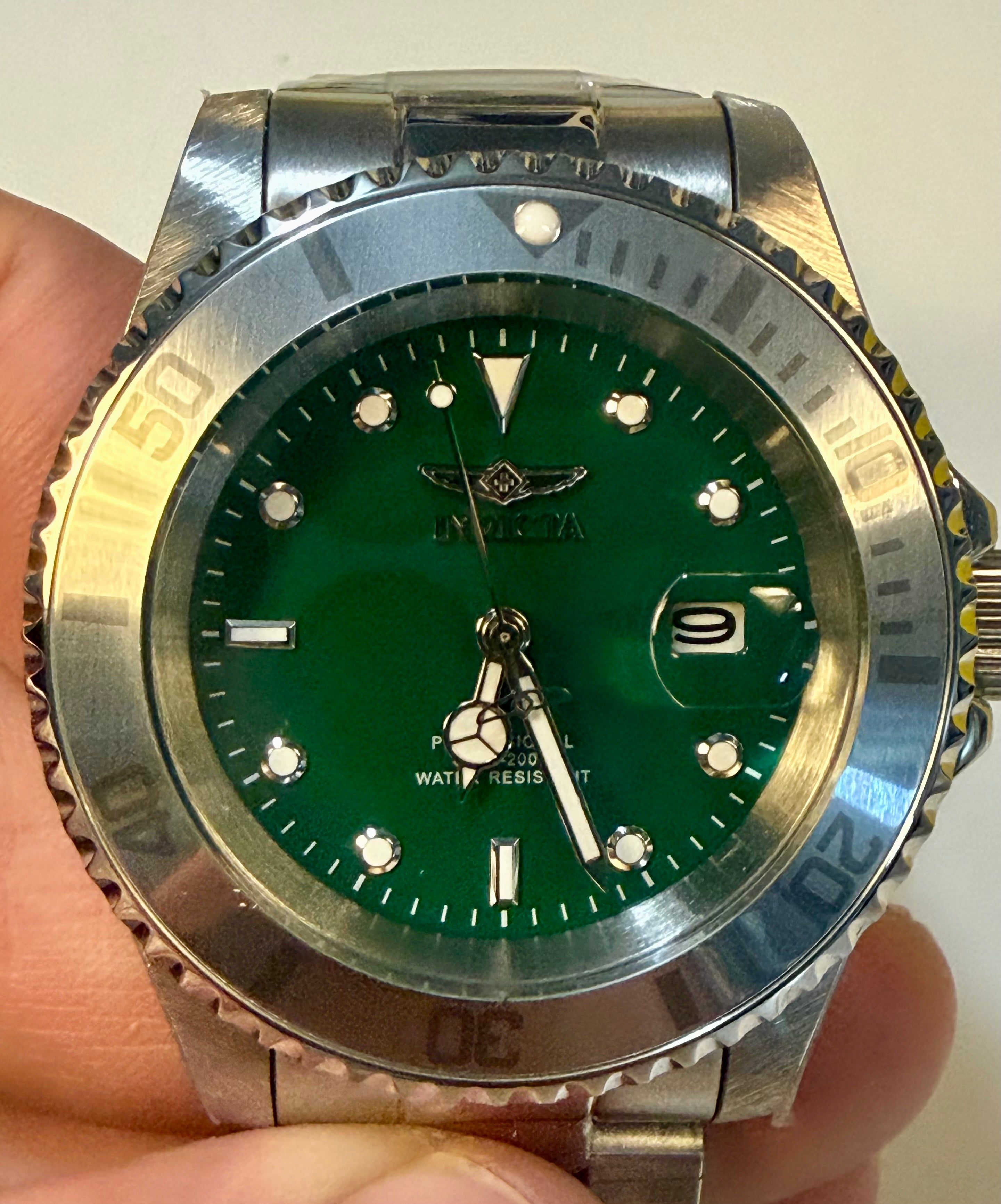 Invicta Mens Pro diver Aurenova 40mm Green watch with silver case held in hand against a white background