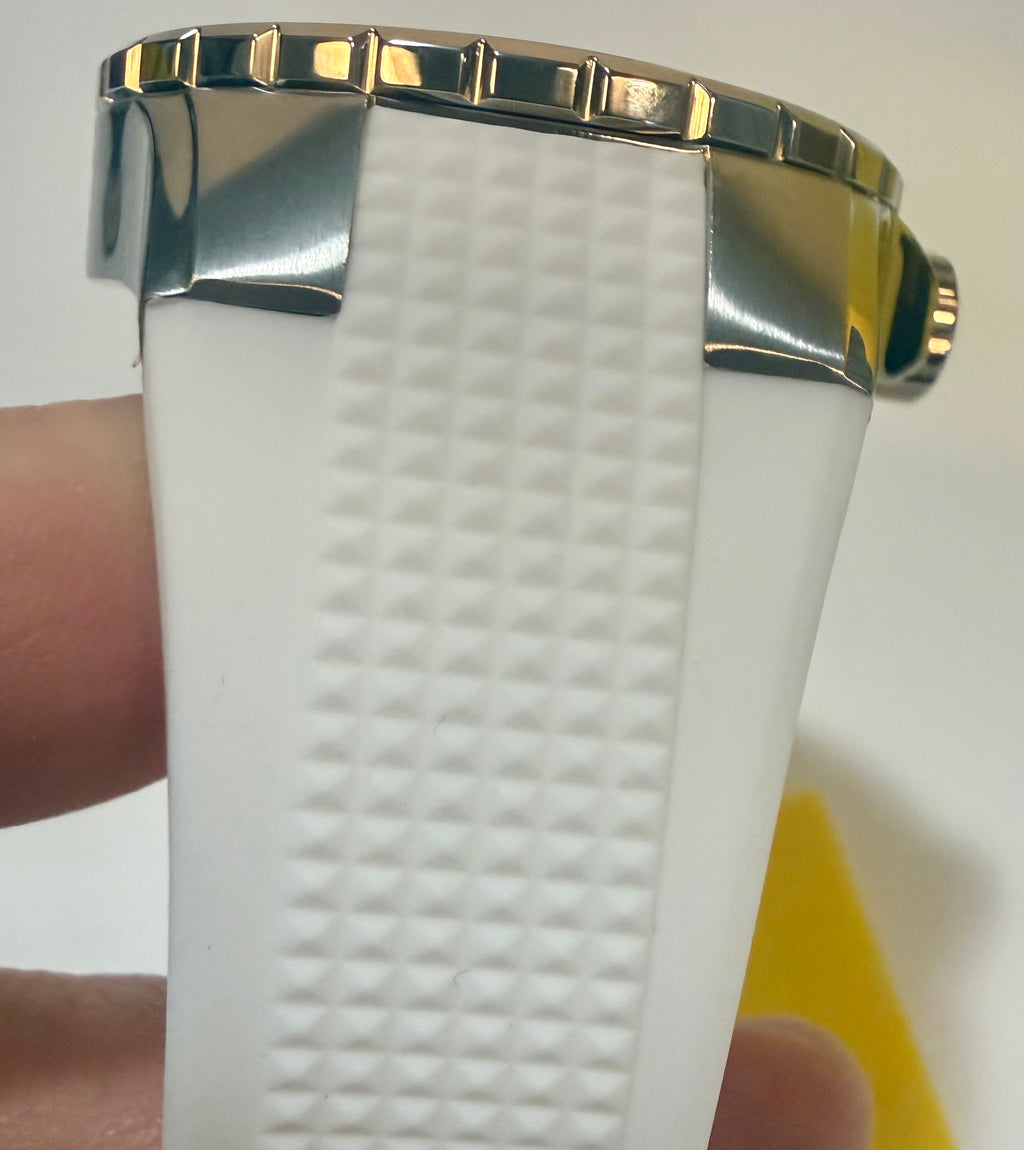 Close-up of a white textured watch band with gold accents held by a hand.