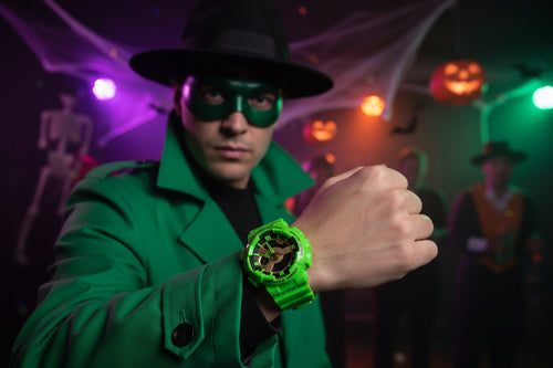 Person in a green trench coat and mask with an Activa green Sports watch, surrounded by Halloween decorations.