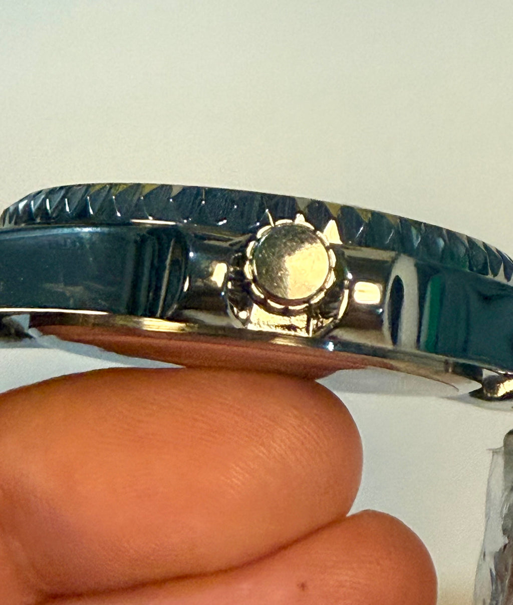 Close-up of a Montres Prestige 42mm Mens Pro Diver  silver watch band held between fingers against a white background
