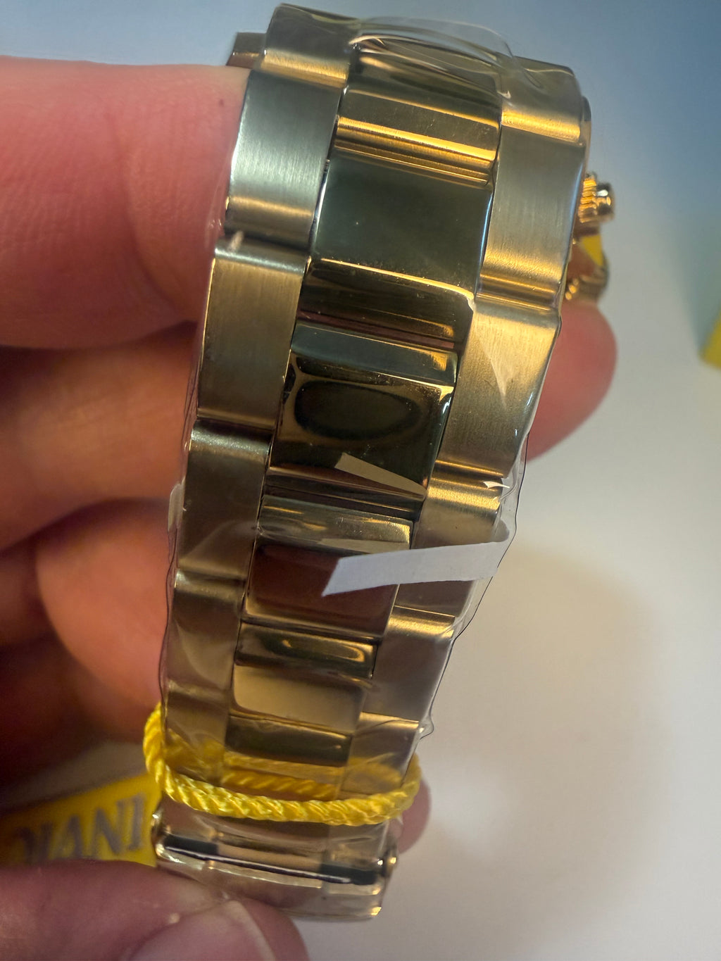 Invicta Speedway Monte Carlo Gold watch band on a person's wrist with a blurred background