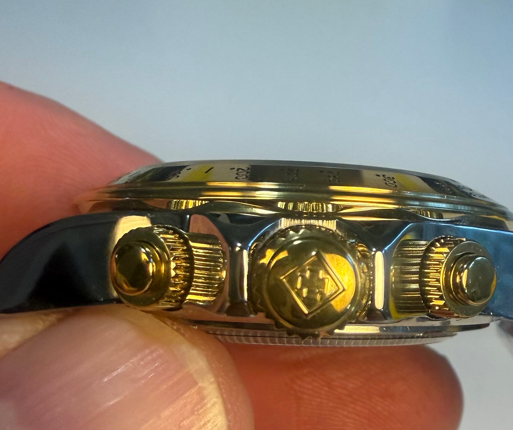 Close-up of a Invicta Speedway Monte Carlo  gold watch case held between fingers with a light gray background