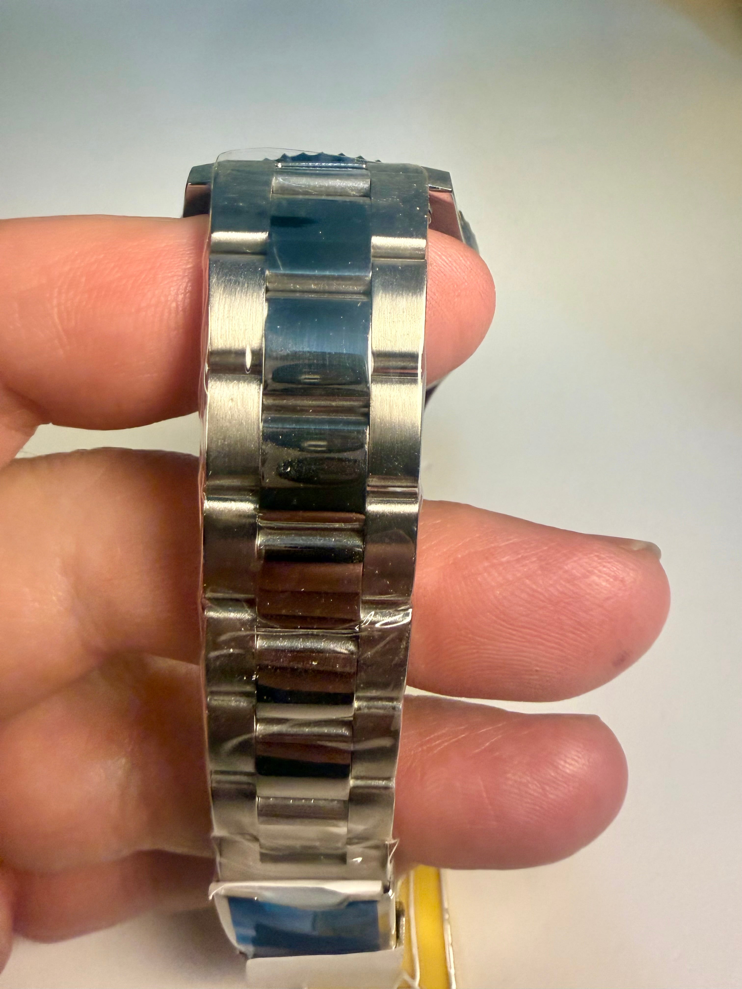 Invicta Specialty Rowan Silver watch band held between fingers against a neutral background