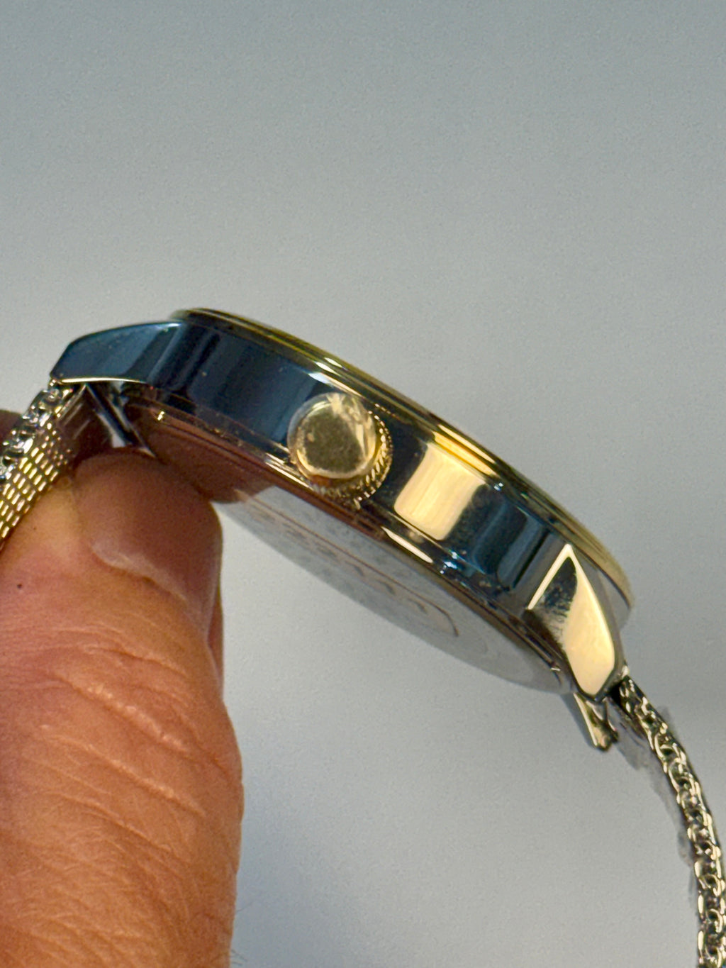 Invicta Mens Specialty Gold watch being held by a hand against a light gray background