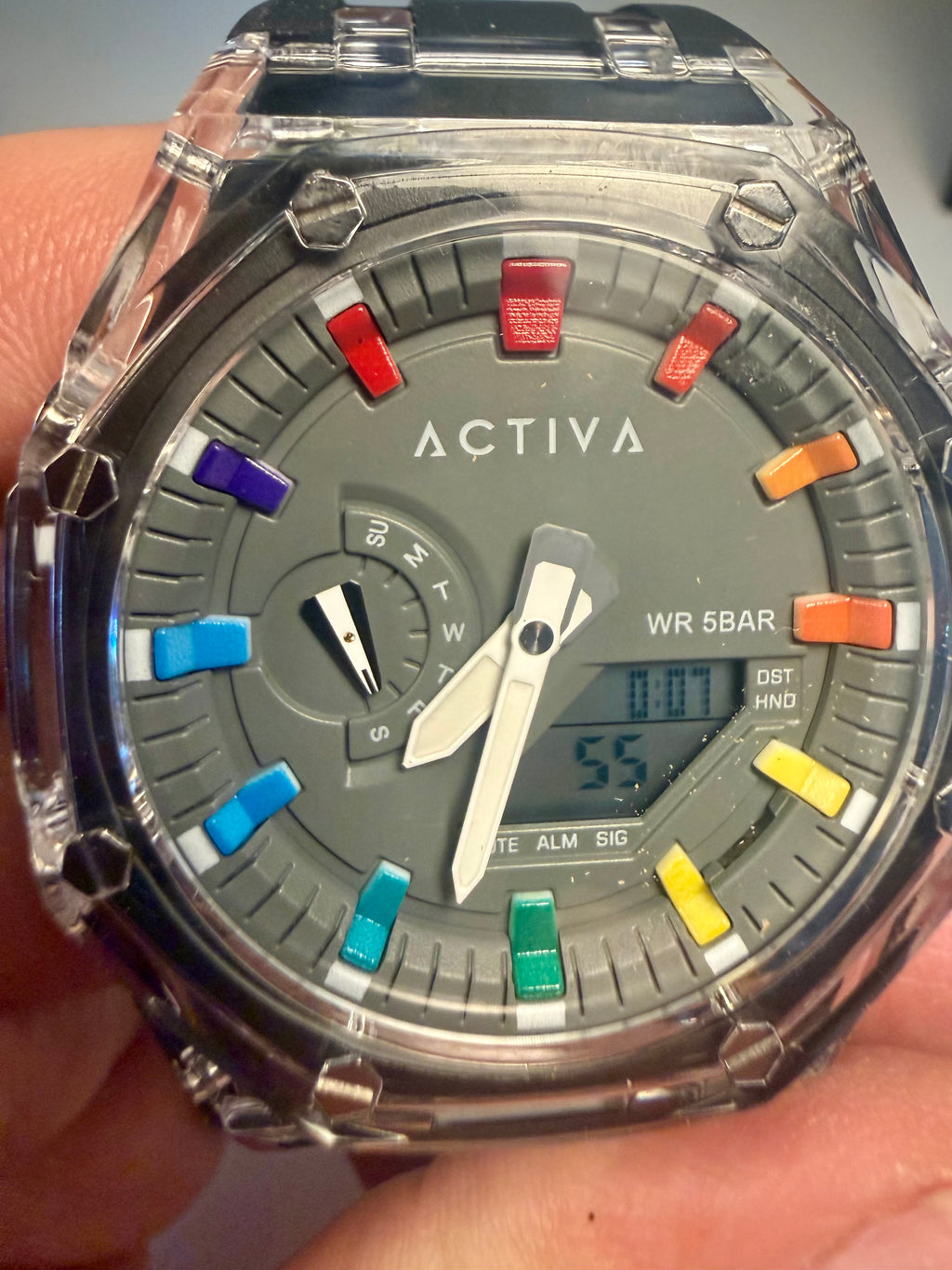 Activa Kaleido Rainbow watch with colorful button accents held in a hand