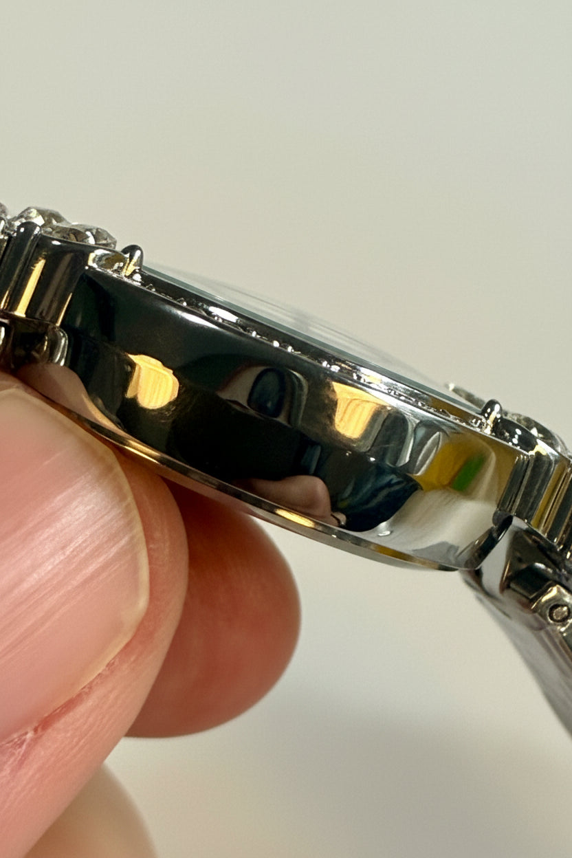 Close-up of a Invicta Ladies Wildflower 30mm  silver watch band held by a hand against a neutral background