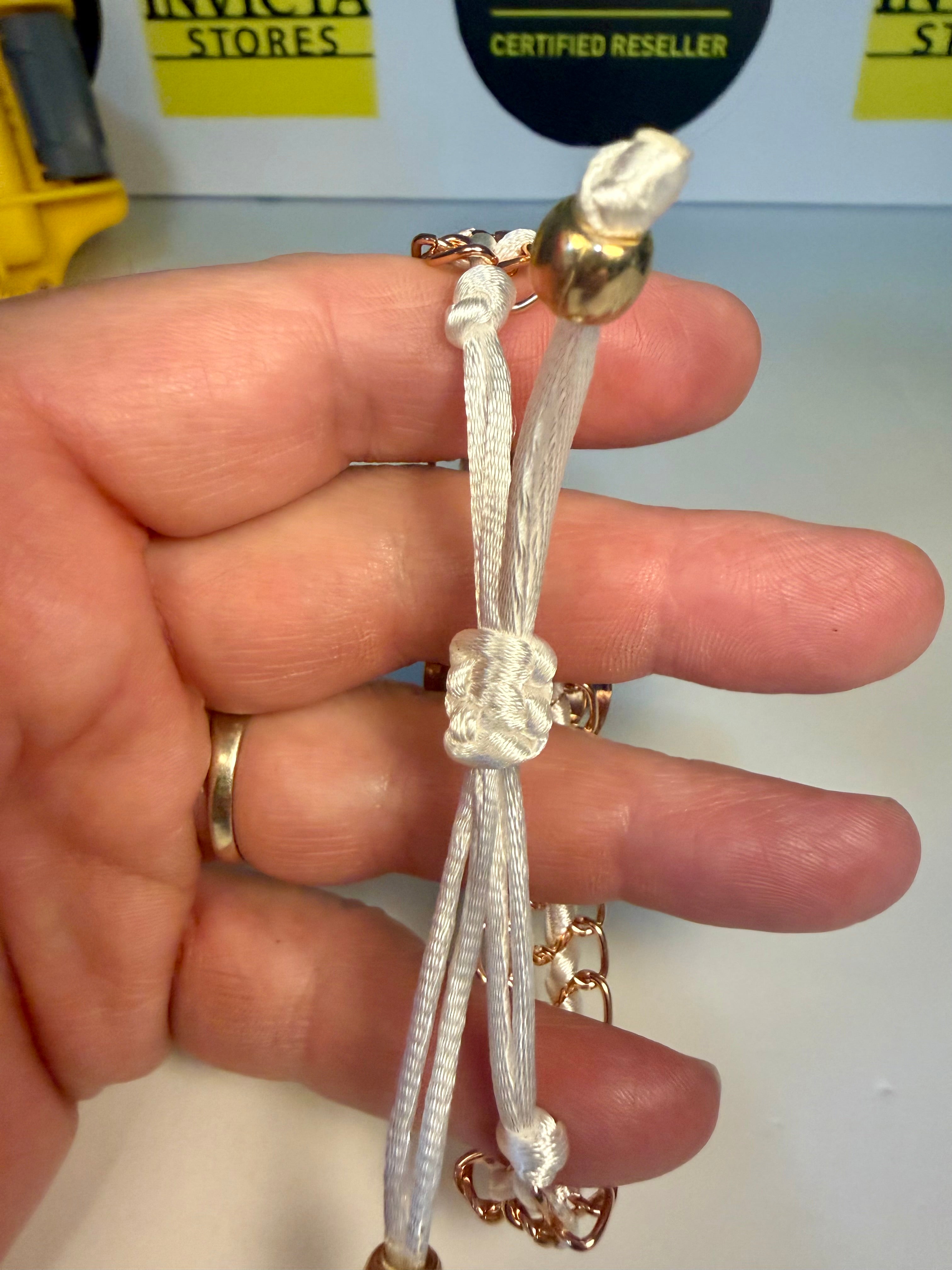 Hand holding a white braided bracelet Ladies Montres Prestige with gold accents against a blurred background