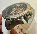 Close-up of a silver wristwatch with a white strap held by a hand.