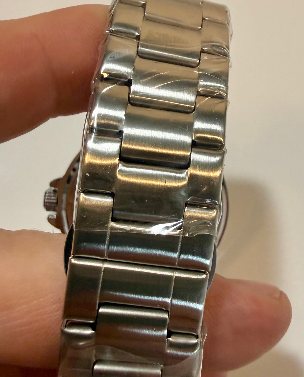 Close-up of a silver watch on a wrist with a plain background