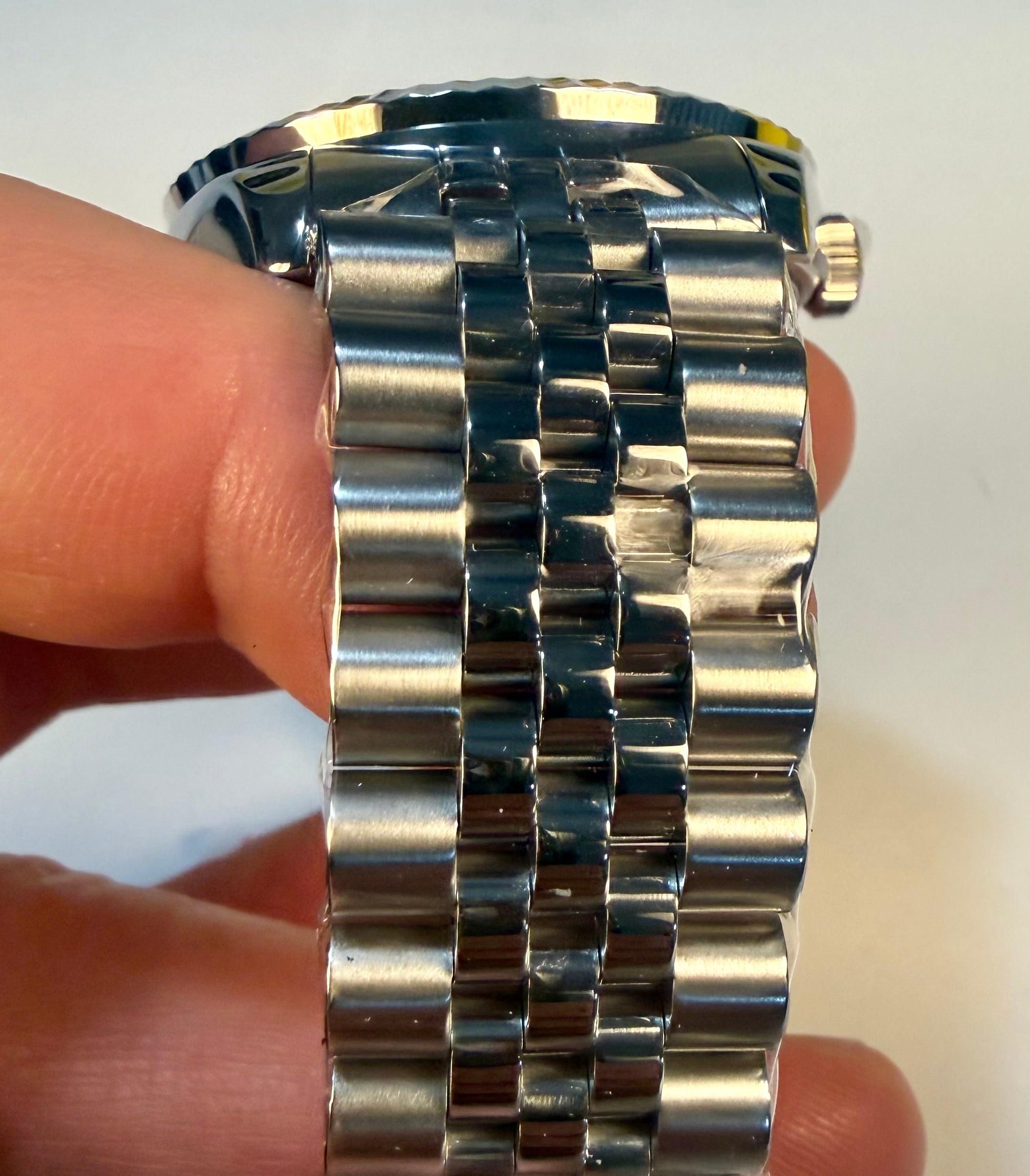Close-up of a Mens Specialty Rowan 43mm held between fingers against a white background