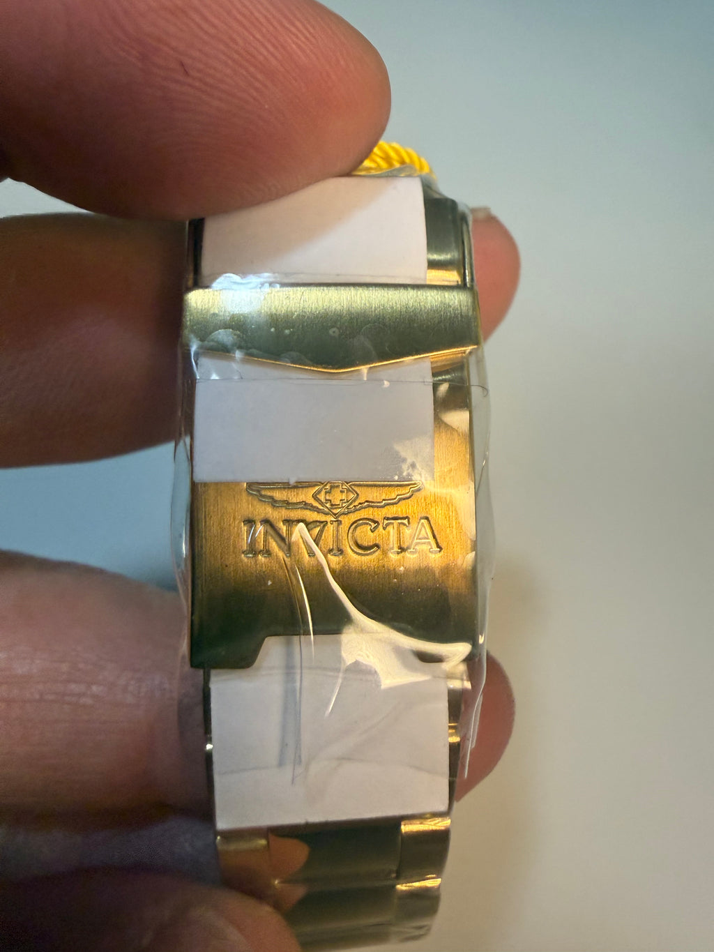 Invicta 38mm Unisex Pro Diver watch band with Invicta logo held between fingers against a neutral background