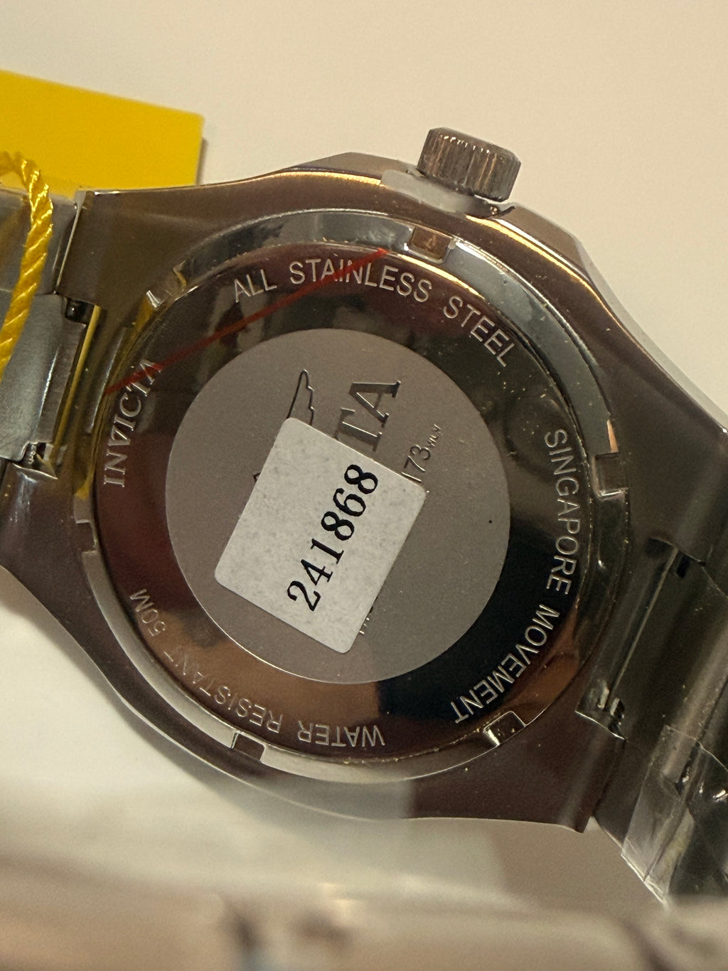 Close-up of a watch case with 'Singapore Movement' and 'Water Resistant' text on a white background.