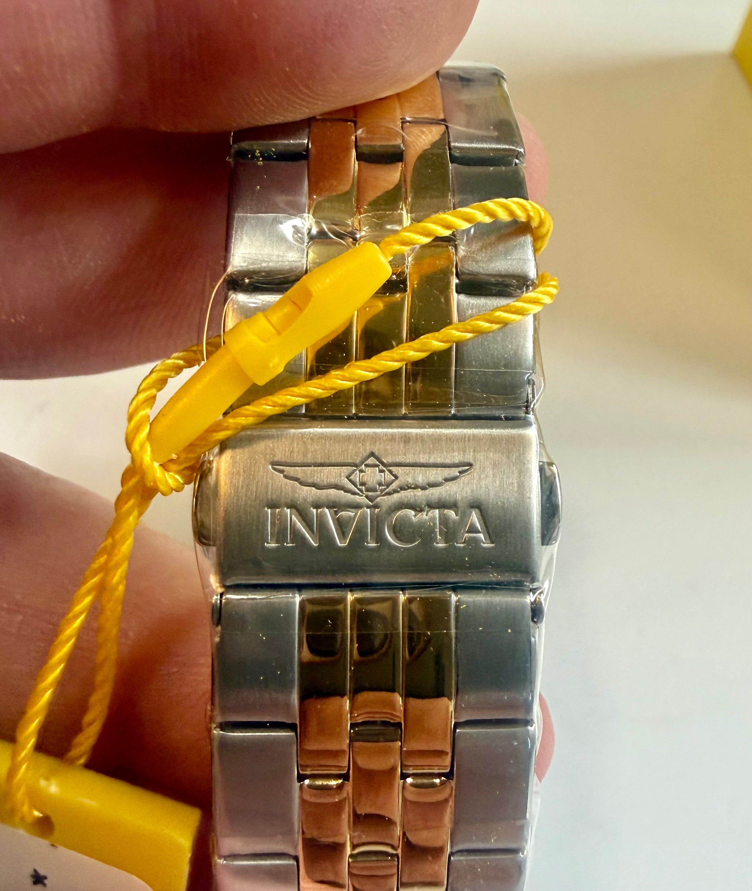 Invicta Ocean Voyage 38mm Pro Diver watch band with yellow strap on a hand against a white background
