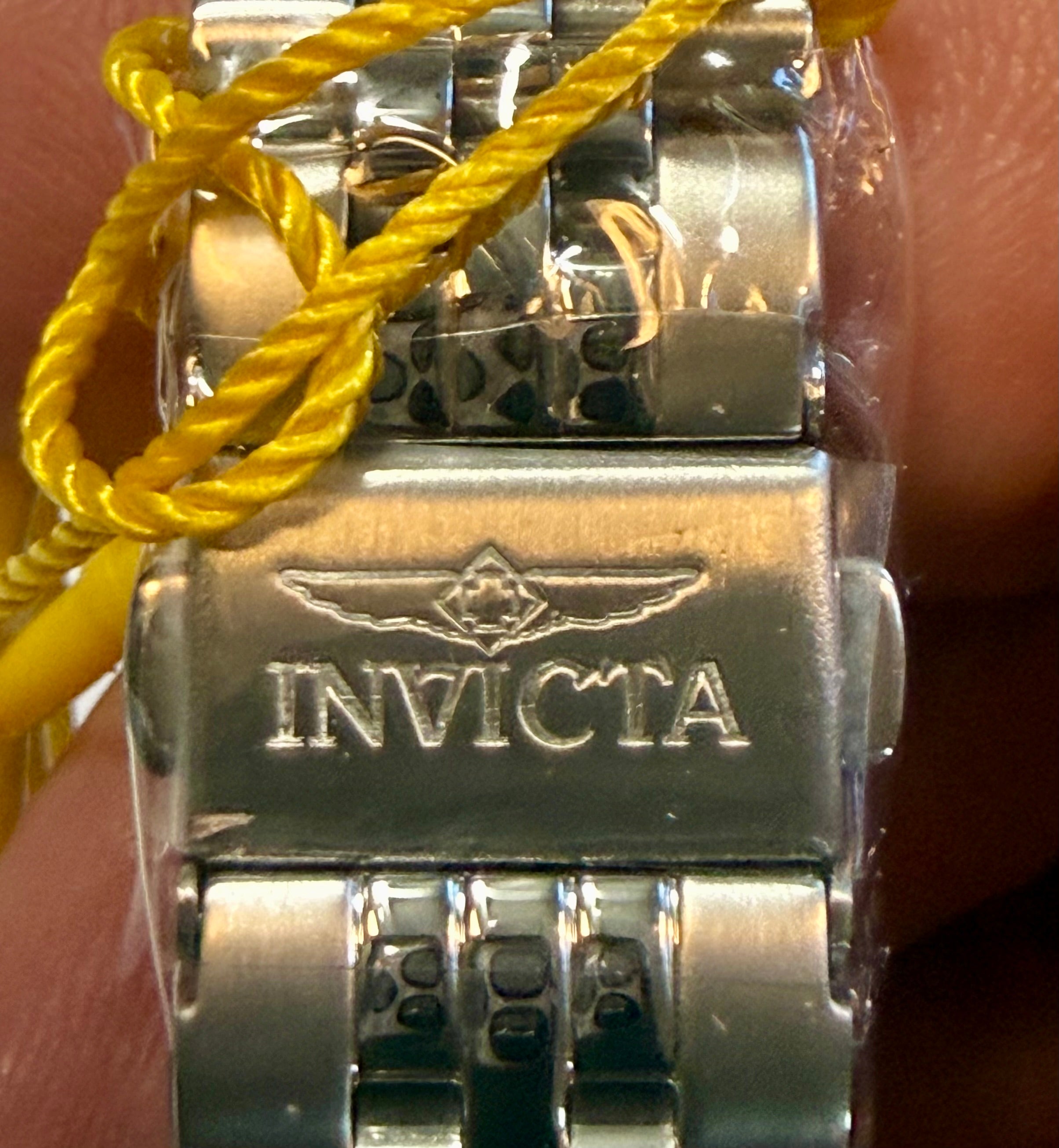 Close-up of a silver Invicta watch clasp with yellow cord